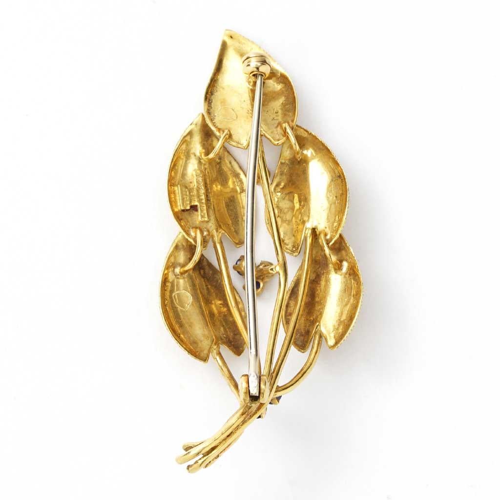 The brooch is 24mm wide, 2.25 inches in length, made of 18K yellow gold, and weighs 6.40 DWT (approx. 9.95 grams). It also has seven round sapphires.