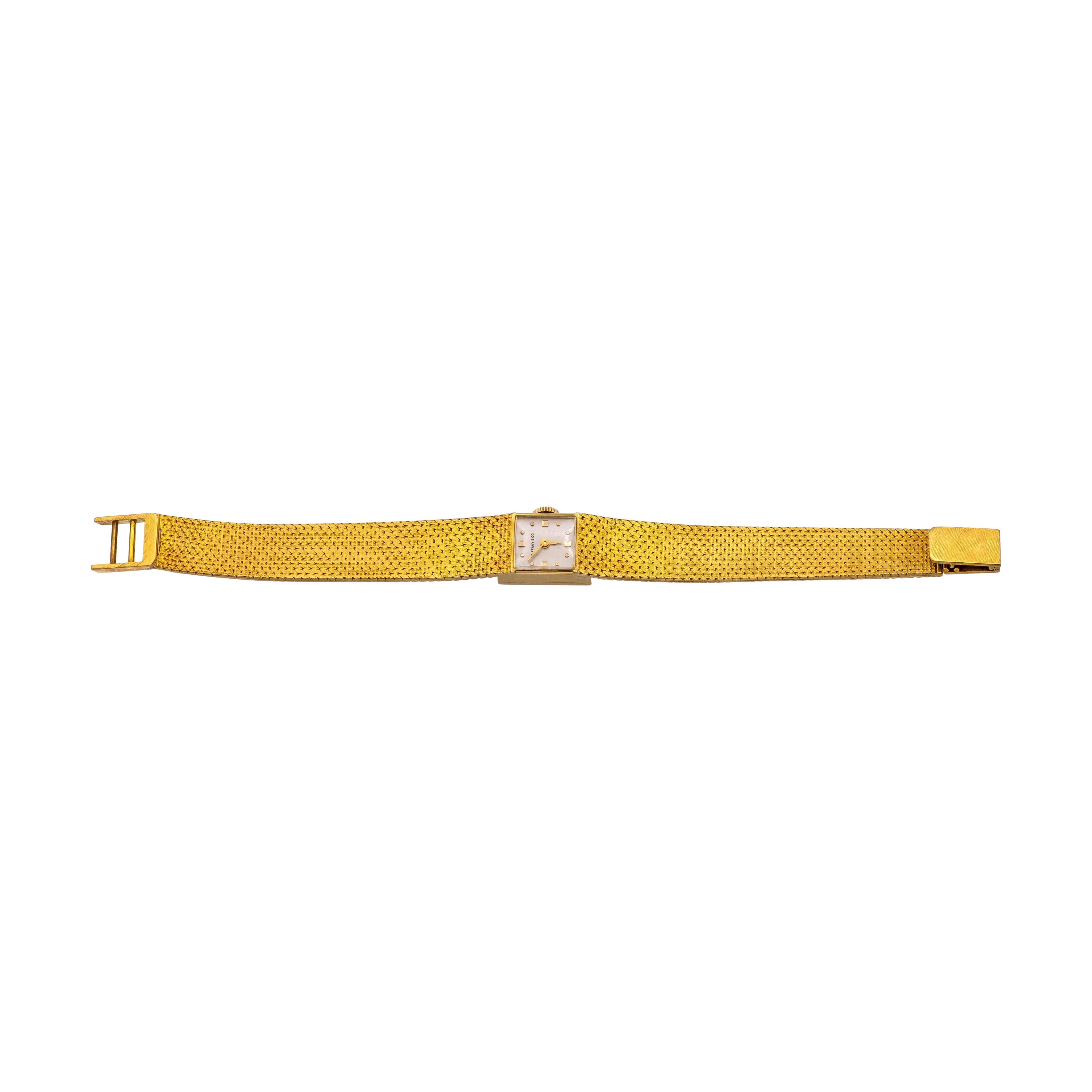 This Tiffany & Co. vintage square watch, crafted in 18K yellow gold, features a mesh bracelet design and a 13.2mm x 13.2mm square case. The watch is powered by a manual winding mechanical movement and showcases sword-shaped hands made of 18K yellow