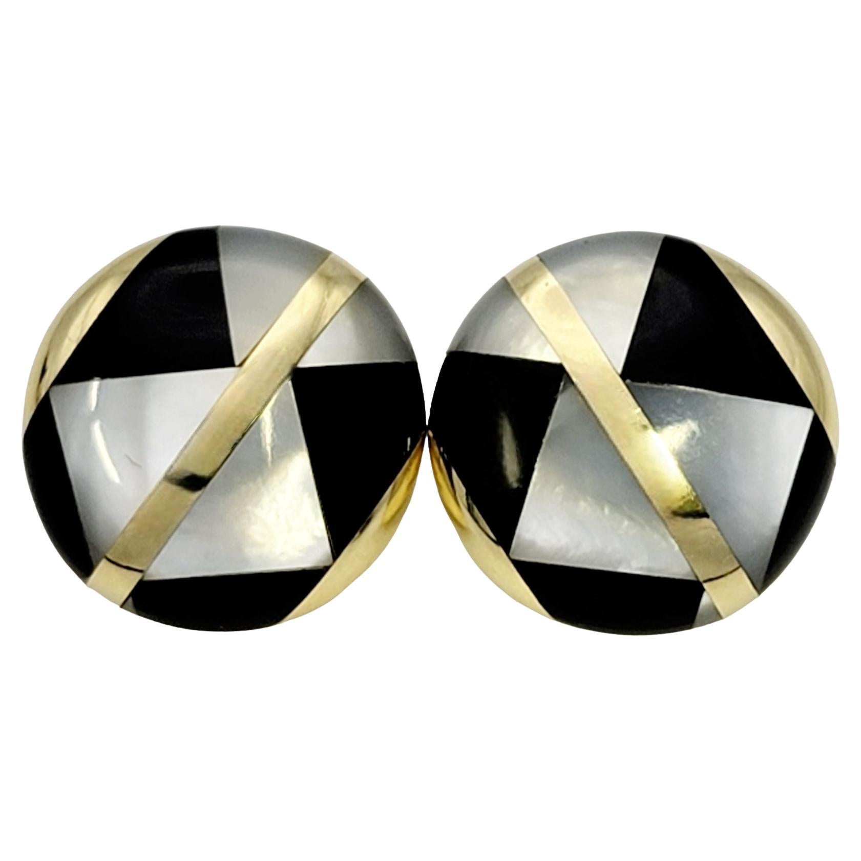 Stunning vintage earrings from Tiffany & Co.. These stylish designer earrings are made of luxurious 18 karat yellow gold and feature a geometric pattern made of Mother of Pearl and black onyx. The perfect button shape clips snugly to the ear,