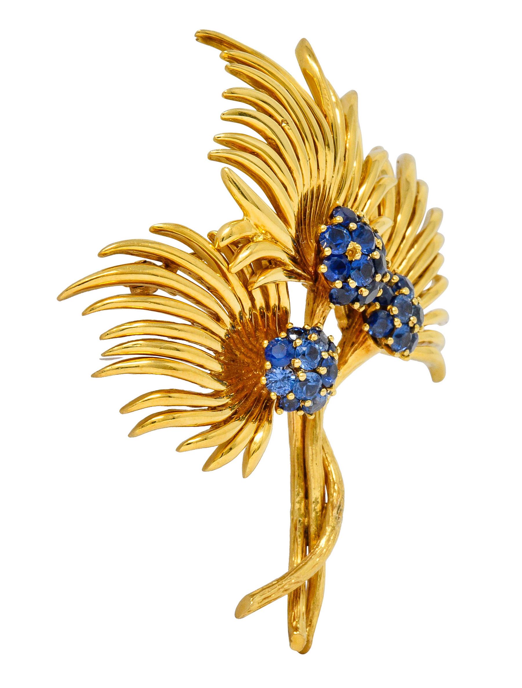 Brooch is designed as three stylized flowers comprised of polished gold tendrils and intertwined stems

Each flower centers a cluster of bright blue to violetish-blue round cut sapphires

Weighing in total approximately 3.56 carats

Completed by pin