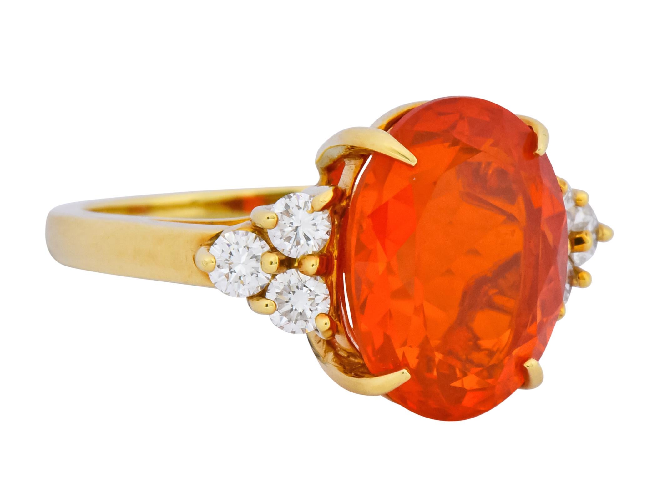 Centering a claw set oval cut fire opal weighing approximately 4.50 carats, transparent and glowing orange in color

Flanked by round brilliant cut diamonds, prong set in triangular formations, weighing approximately 0.36 carat, G/H color and VS