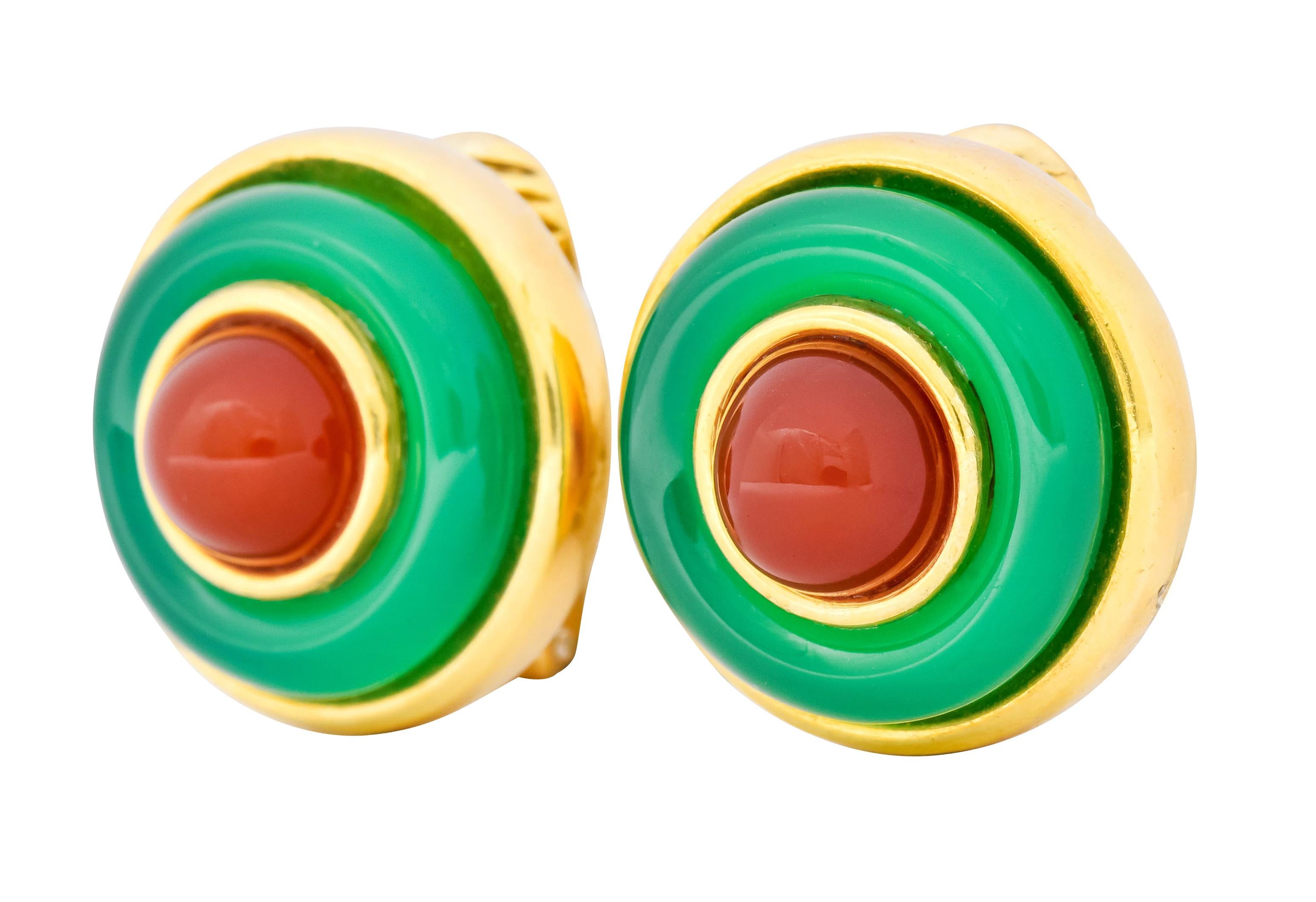 Each earring centers a round carnelian cabochon measuring approximately 7.5 mm, translucent and brick red in color

Surrounded by a carved ring of chrysoprase, translucent and a lush green in color

Both bezel set in a polished gold
