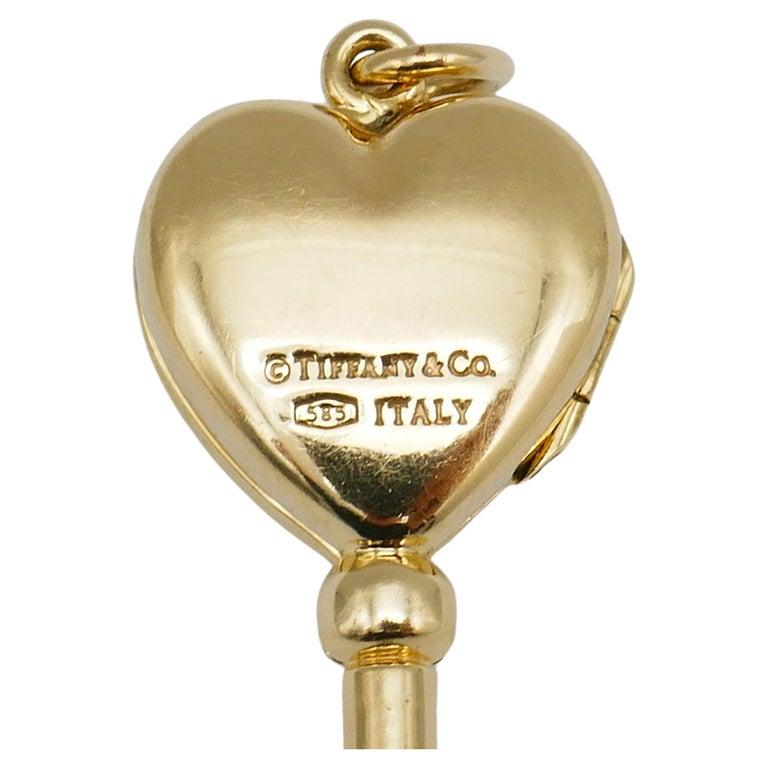 A cute vintage yellow gold Heart Key pendant by Tiffany & Co. 
The top heart part features a locket. Stamped with Tiffany & Co. maker's mark, a hallmark for 14k gold and a country of origin (Italy).
Measurements: 2 3/8