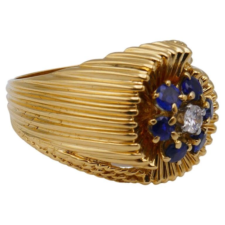 A beautiful vintage Tiffany& Co. yellow gold ring with fluted design. Features a single 0.06 pts round cut diamond and six sapphires, total carat weight is ~1/4 carat. 
Stamped with Tiffany&Co. maker's mark and a hallmark for 18k gold.
Measurements: