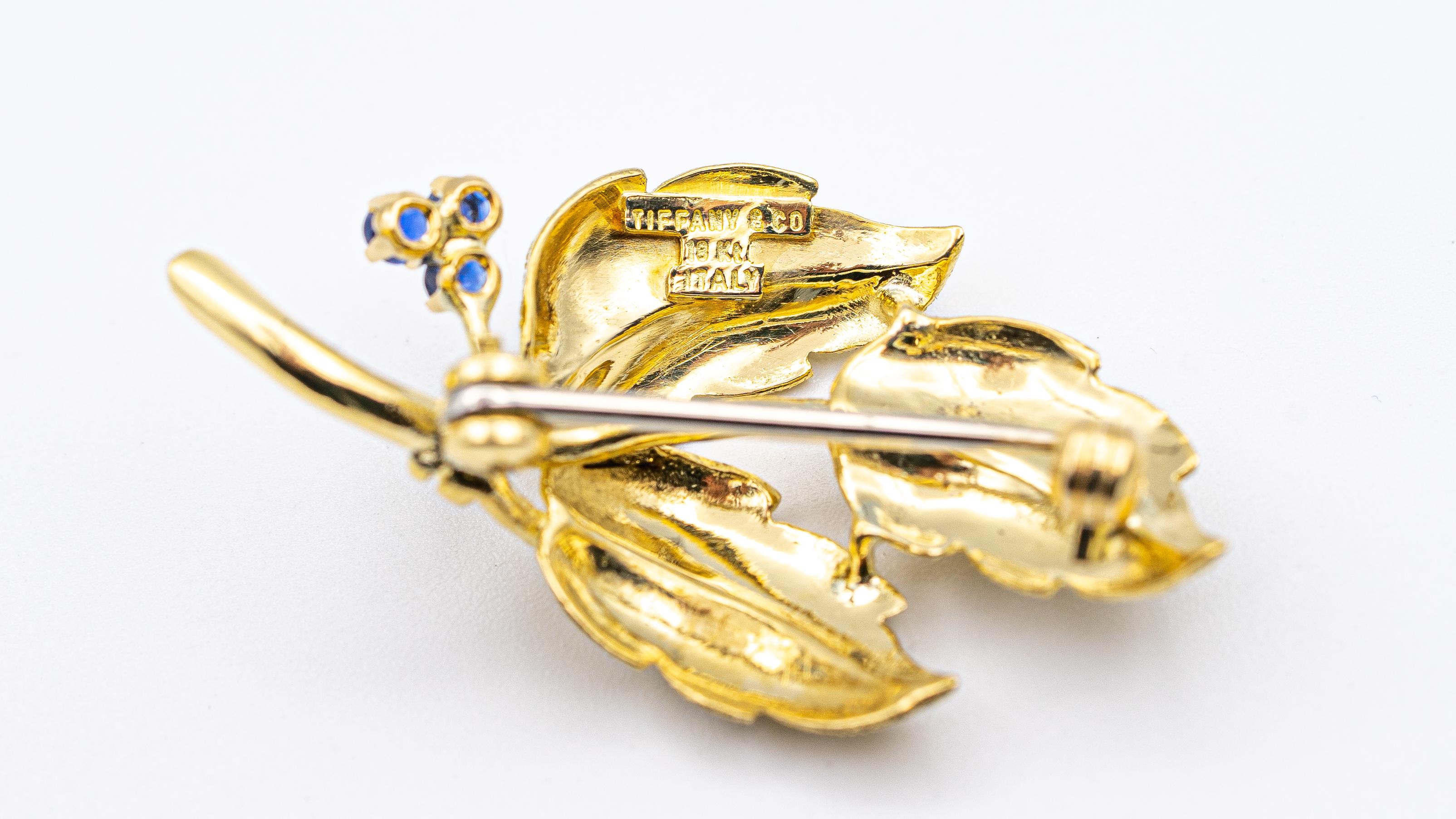 Tiffany & Co. Vintage Sapphire pin finely crafted in Italy, made in 18 Karat yellow gold with 3 round deep blue sapphires. Gold has a Florentine satin finish with detailed patterns on the leaves.

Hallmarks: Tiffany & Co. Italy 18K
Measurements:
