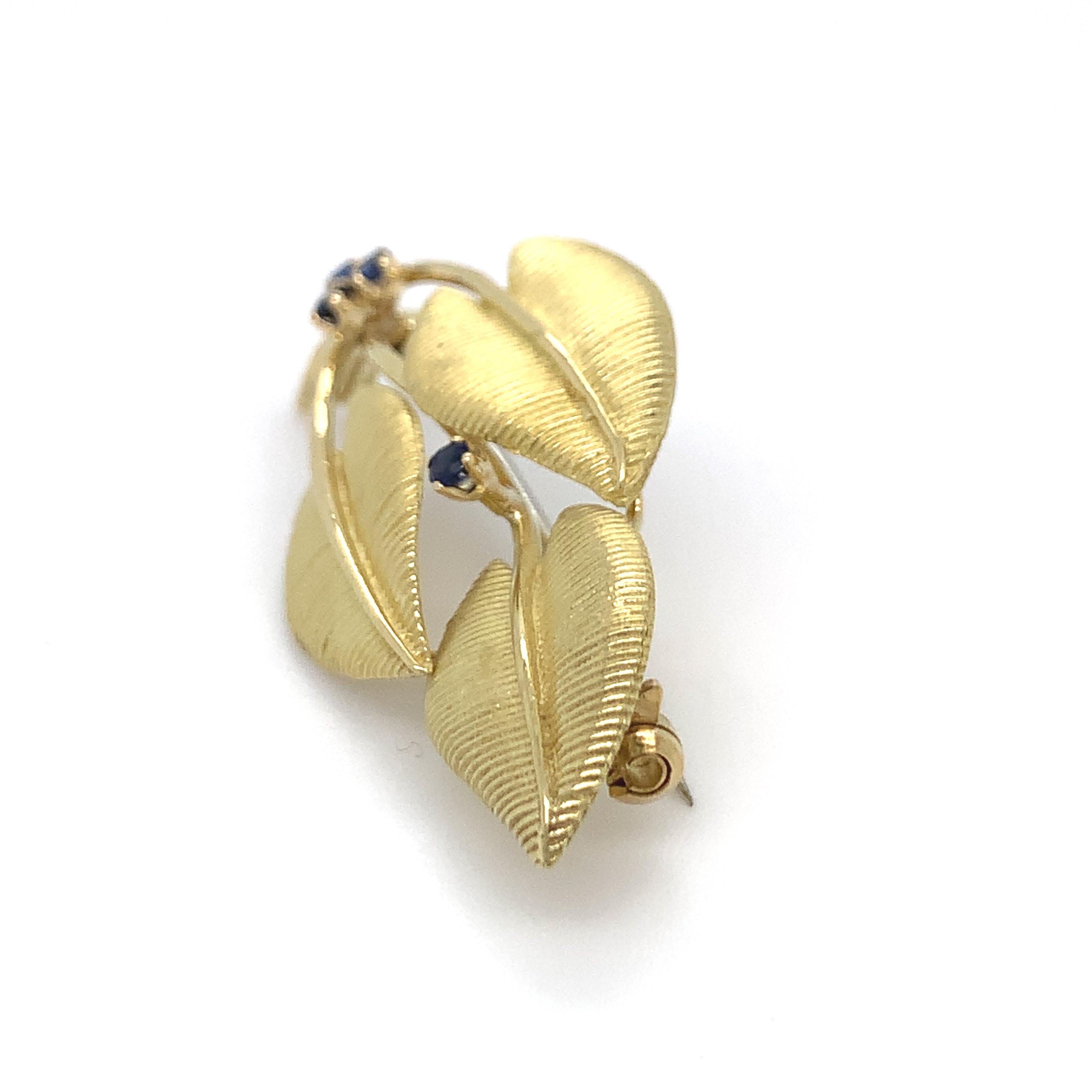 Tiffany & Co. Broche vintage con motivo de hoja finamente elaborado en oro amarillo de 18 quilates con acabado satinado florentino sobre oro pulido con 4 zafiros facetados de color azul intenso engastados con un peso total aproximado de 0,12