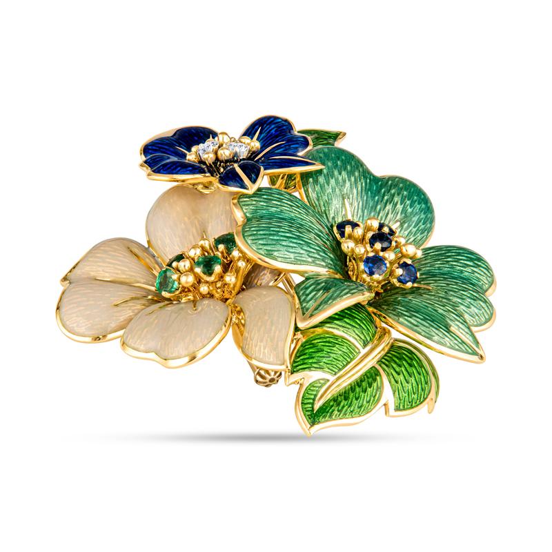 This extremely rare and beautiful enamel brooch from Tiffany & Co. features three beautiful flowers accented by sapphires, diamonds, and emeralds set in 18 karat yellow gold. It is a very unique piece that will be sure to turn heads. Wear alone or