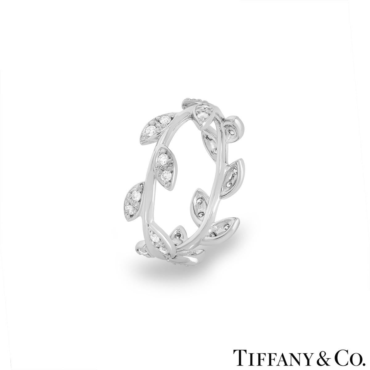 A delicate 18k white gold diamond ring by Tiffany & Co. from Paloma Picasso's Olive Leaf collection. The ring features a leaf design wrapped around a stem and pave set with 28 round brilliant cut diamonds totalling approximately 0.28ct, E-F colour