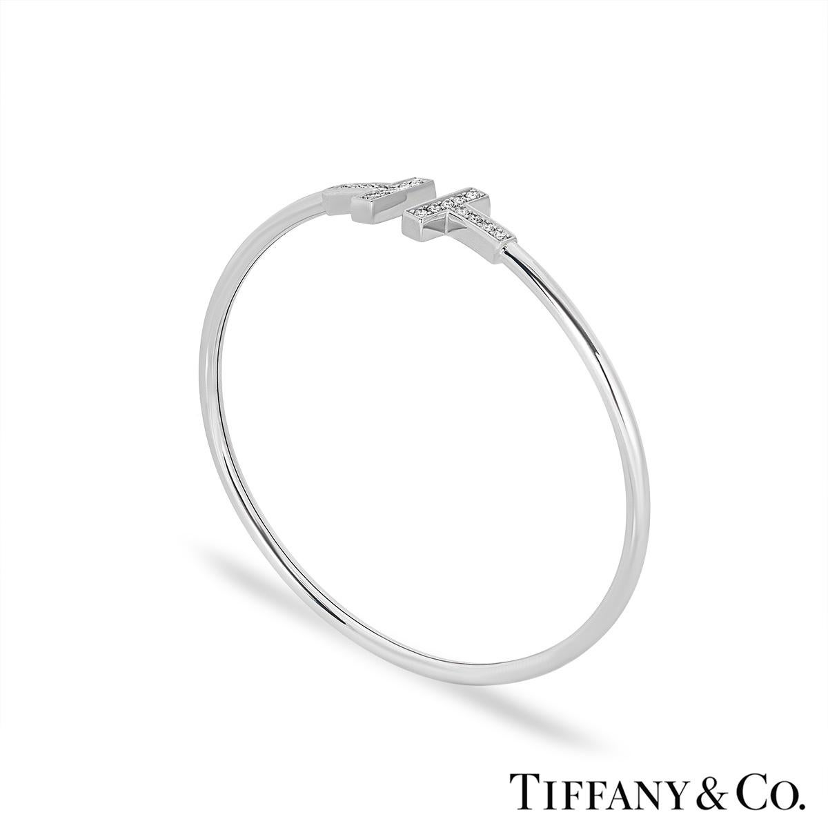A timeless 18k white gold diamond bracelet by Tiffany & Co. from the Tiffany T collection. The bracelet comprises of two iconic Tiffany T motifs in a cuff style, pave set with 18 round brilliant cut diamonds with an approximate weight of 0.24ct, F-G