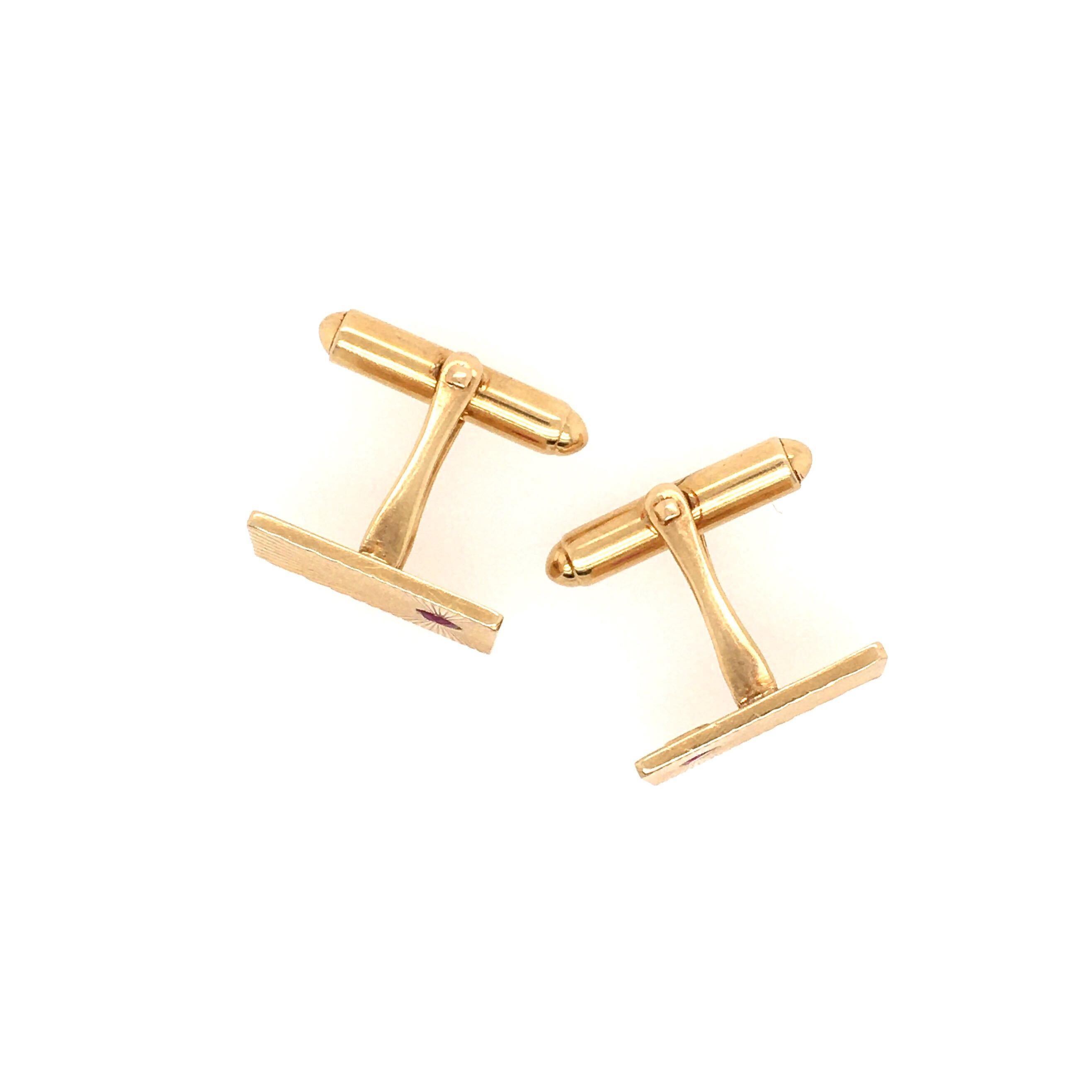 A pair of 14 karat yellow gold and ruby cufflinks with spring links, circa 1940s, Tiffany.  The face of each rectangular cufflink is set with a 3mm round faceted ruby toward one end, with a sunray pattern radiating from around the ruby.  Each