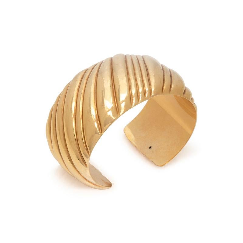 This Tiffany & Co. ribbed 18K yellow gold bracelet is 35mm wide and has a 6.5 inch inner circumference. Gross weight: 32.90 dwt. Signed TIFFANY & Co (Italian hallmark) 750 ITALY.
