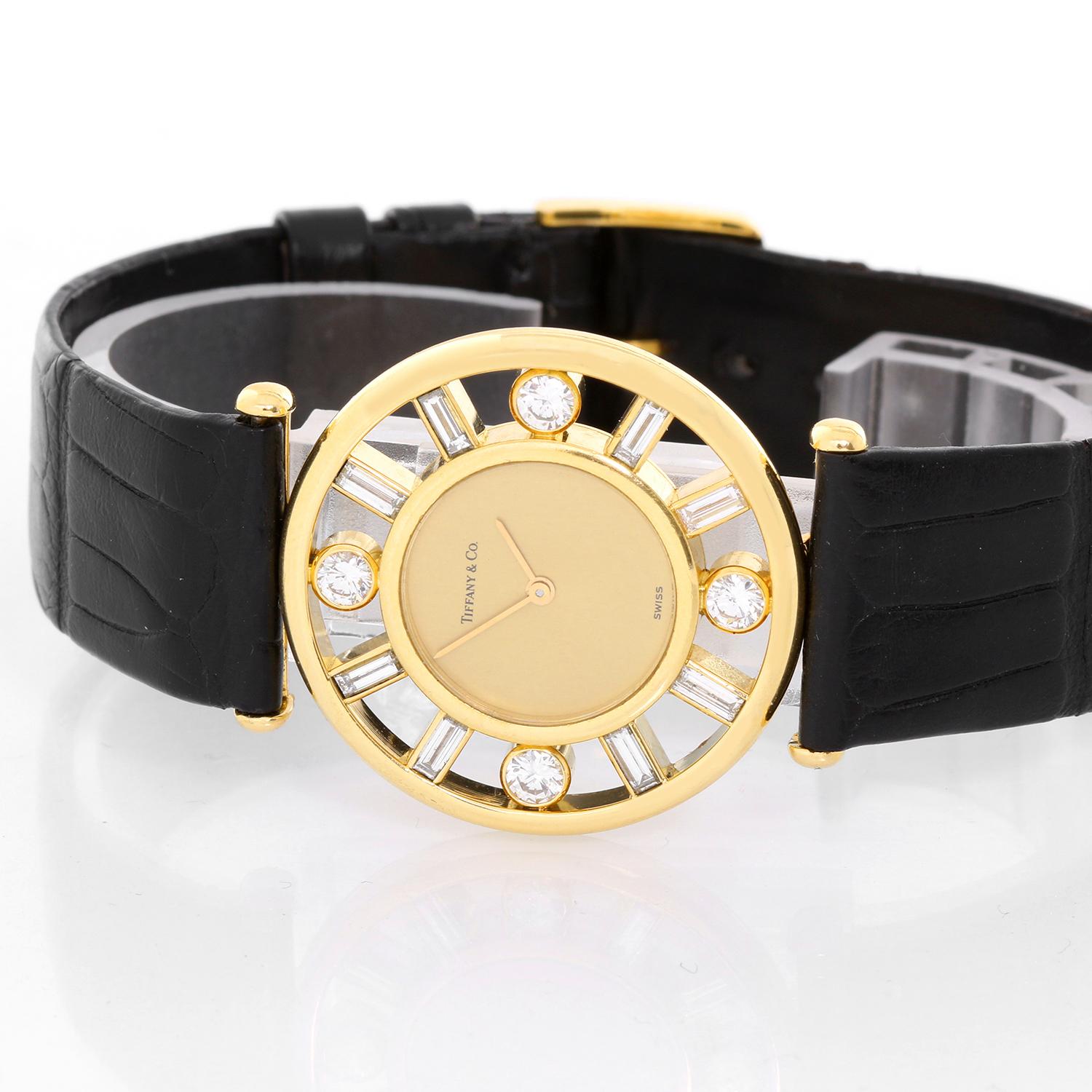 Tiffany & Co. 18K Yellow Gold Classique Watch -  Quartz. 18K Yellow gold ( 31 mm ) with diamond bezel; 4 Round brilliant cut diamonds. Total weight .60 cts and 8 Baguette cut diamonds. Total weight .80 cts.. Champagne dial. Black alligator strap.