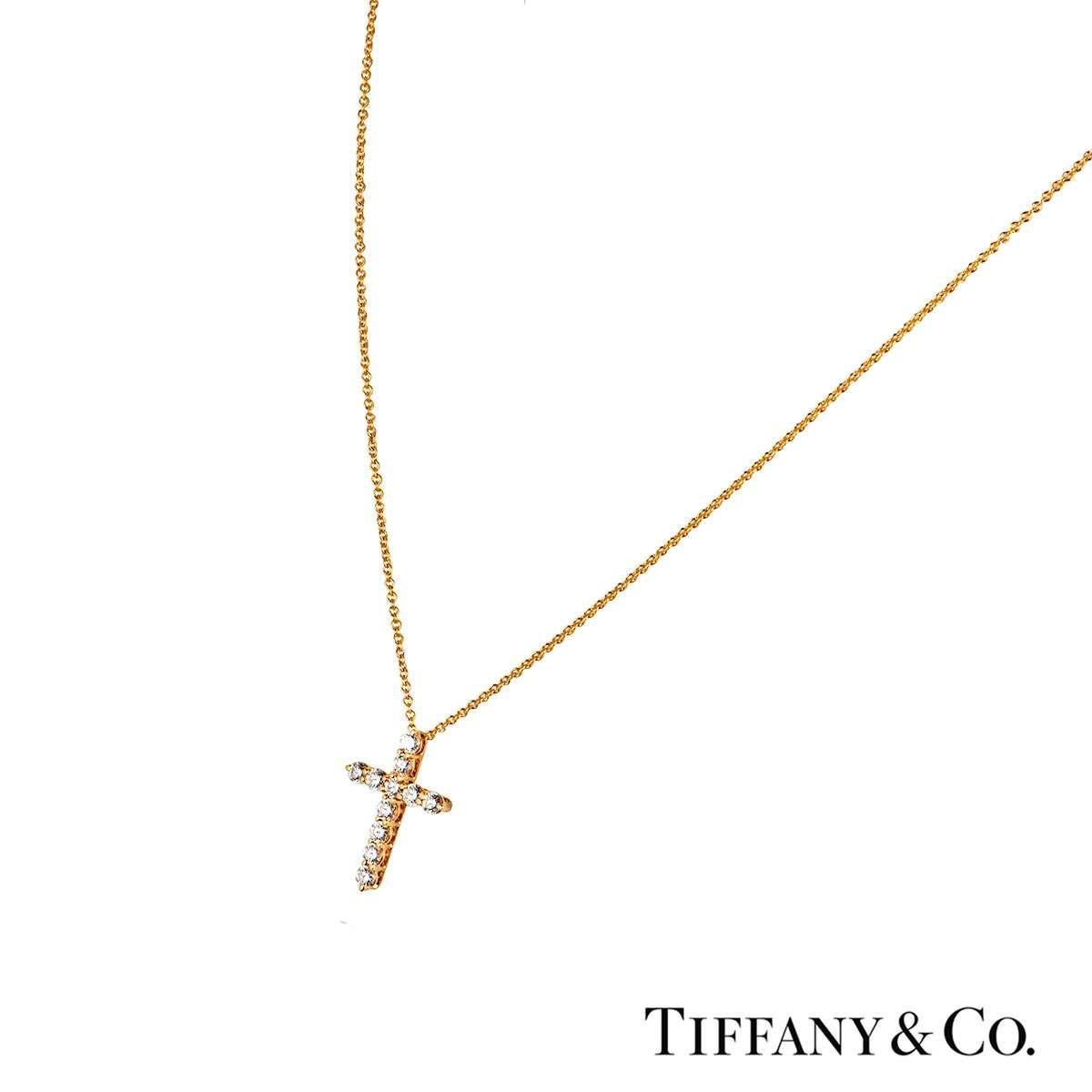 An 18k yellow gold diamond pendant by Tiffany & Co. The pendant features a cross motif which is made up of 11 round brilliant cut diamonds totalling 0.42ct. The pendant features a bolt spring clasp on a 16 inch chain and has a gross weight of 2.50