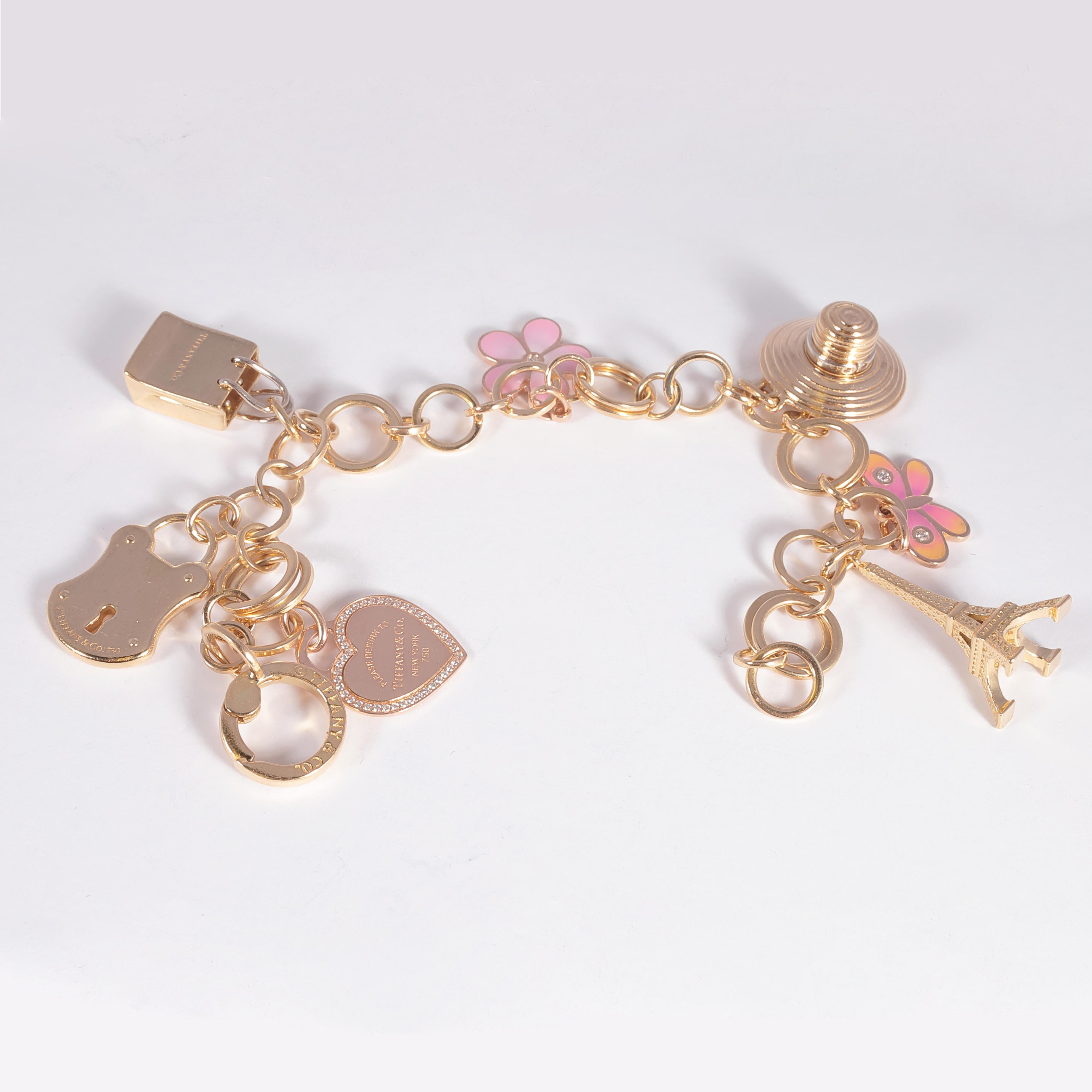 Lovely 18 karat yellow charm gold bracelet by Tiffany & Company, featuring 7 yellow gold charms, 3 with diamonds.  The circular interlocking link bracelet is lovely by itself!