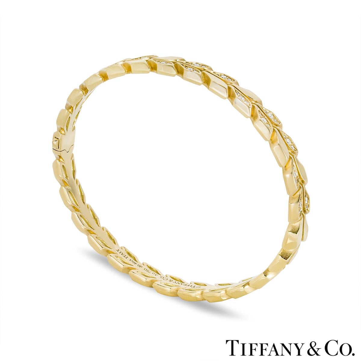 A beautiful 18k yellow gold diamond bangle by Tiffany & Co. from the Victoria Vine collection. The bracelet features a vine design throughout alternating between high polish and diamond set motifs. The 72 round brilliant cut diamonds have an