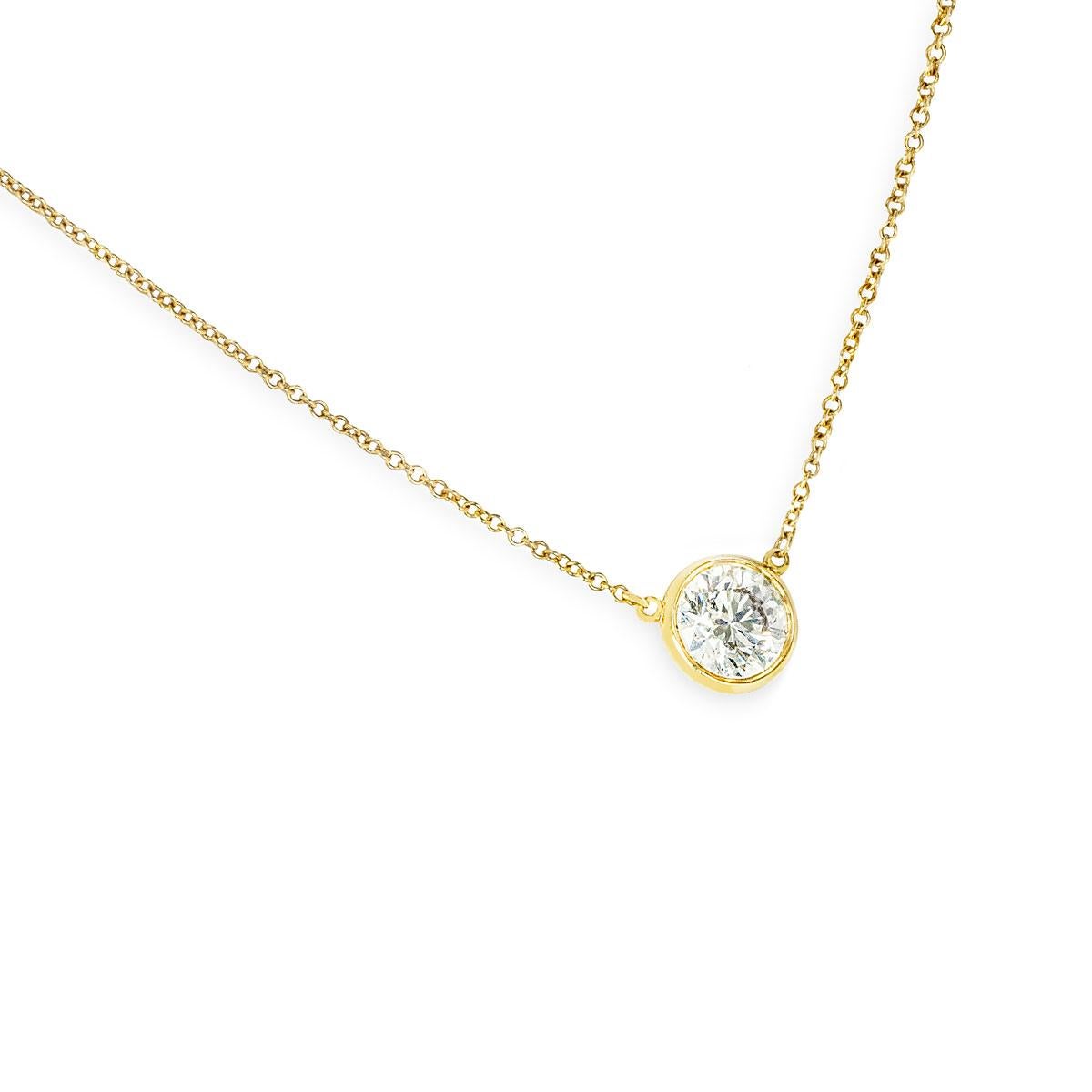 A beautiful yellow gold diamond pendant by Tiffany & Co. from the Elsa Peretti Diamonds By The Yard collection. The pendant features a bezel set round brilliant cut diamond weighing 1.20ct, H colour and VVS1 clarity. The diamond scores an excellent