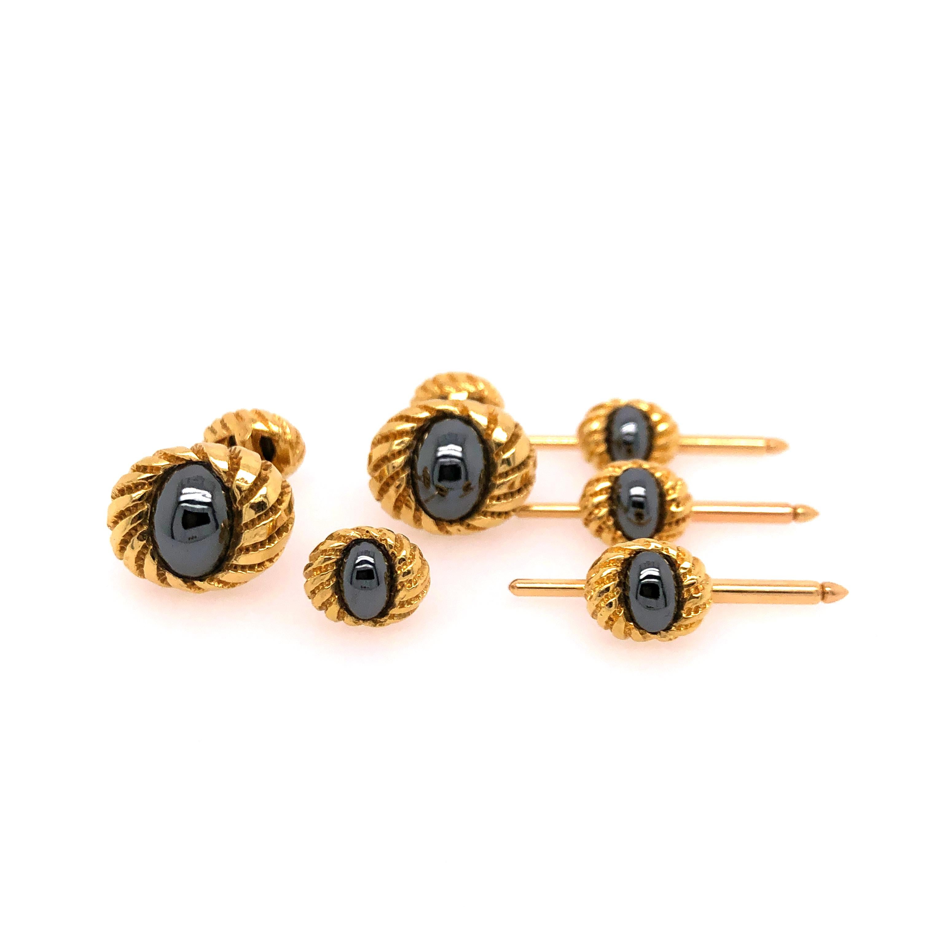 Tiffany's yellow gold 6 piece Tuxedo Set includes two cufflinks and 4 buttons. The oval hematite stones are set center in the 18K yellow gold swirled settings. 

Stamped: Tiffany 18K, Schlumberger