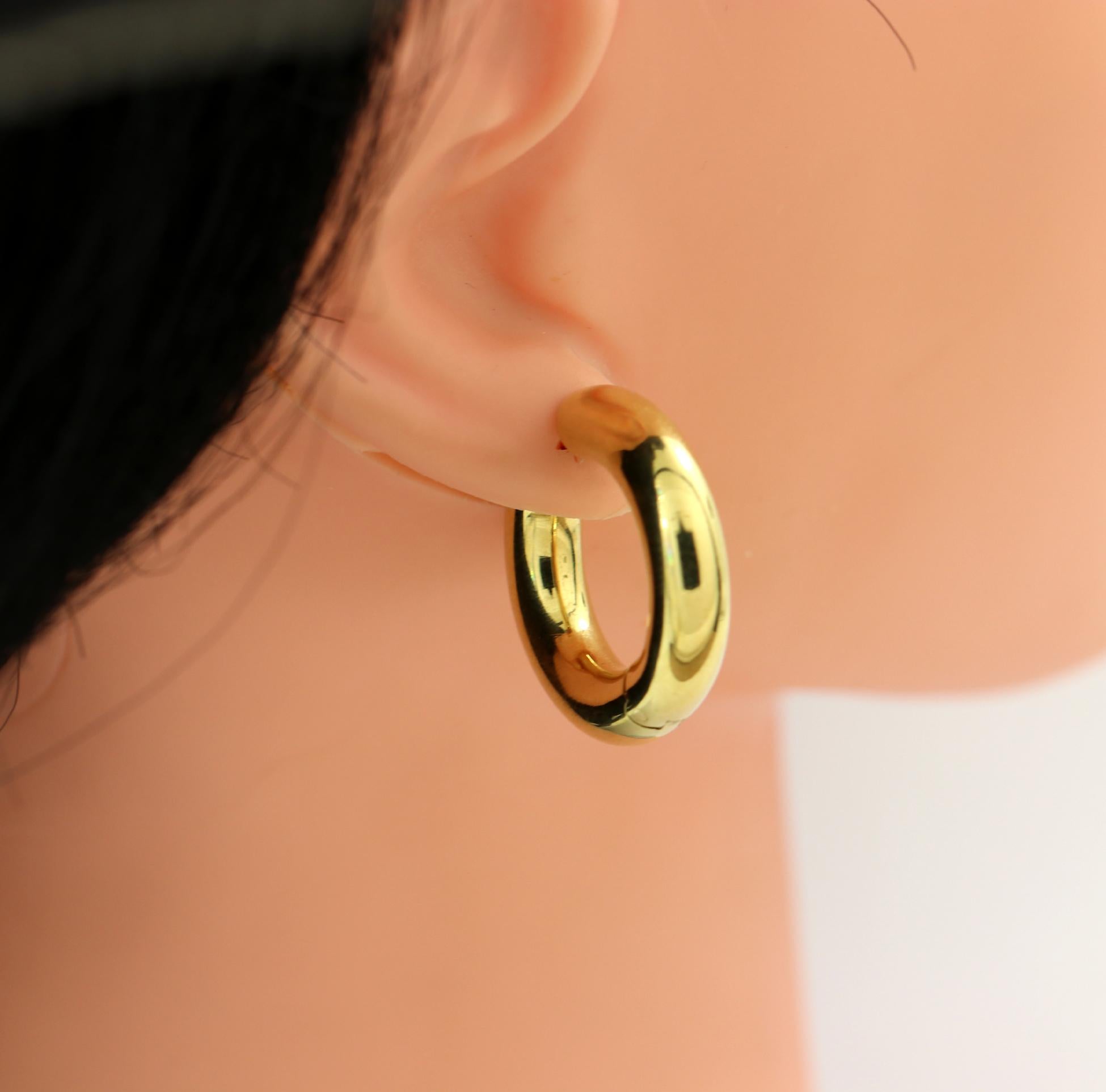 A pair of ladies 18K yellow gold hoop earrings, with an outer thickness of 1/4 inch, and measuring a little over an inch in diameter. Marked Tiffany & Co. Italy, and 750. The walls are thick allowing for strong construction while being a hollow