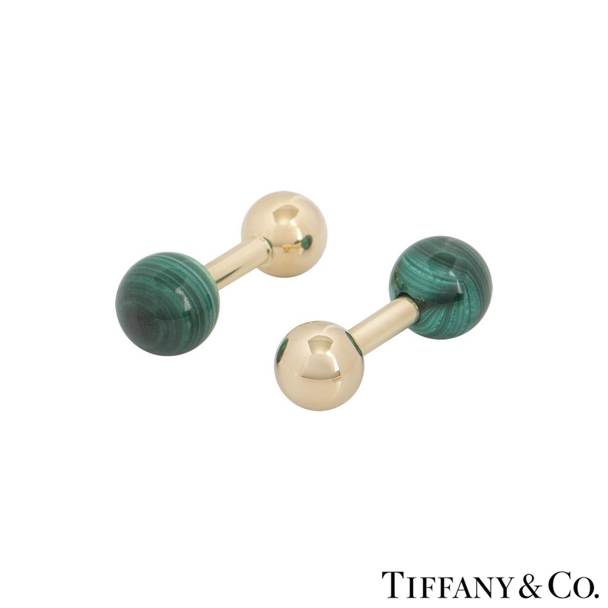 A pair of 14k yellow gold malachite ball cufflinks by Tiffany & Co. The cufflinks each feature a malachite bead on one end and a yellow gold polished ball on the other. The cufflinks are encased together by a bar fitting with a length of 2.70cm with