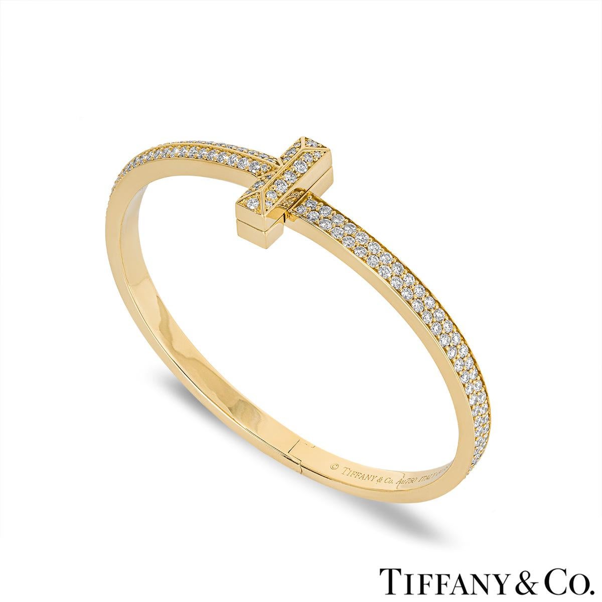 An extravagant 18k yellow gold diamond bracelet by Tiffany & Co. from the Tiffany T collection. The diamond set bracelet wraps around the wrist with the iconic Tiffany T motif at the centre. The 202 round brilliant cut diamonds are pave set