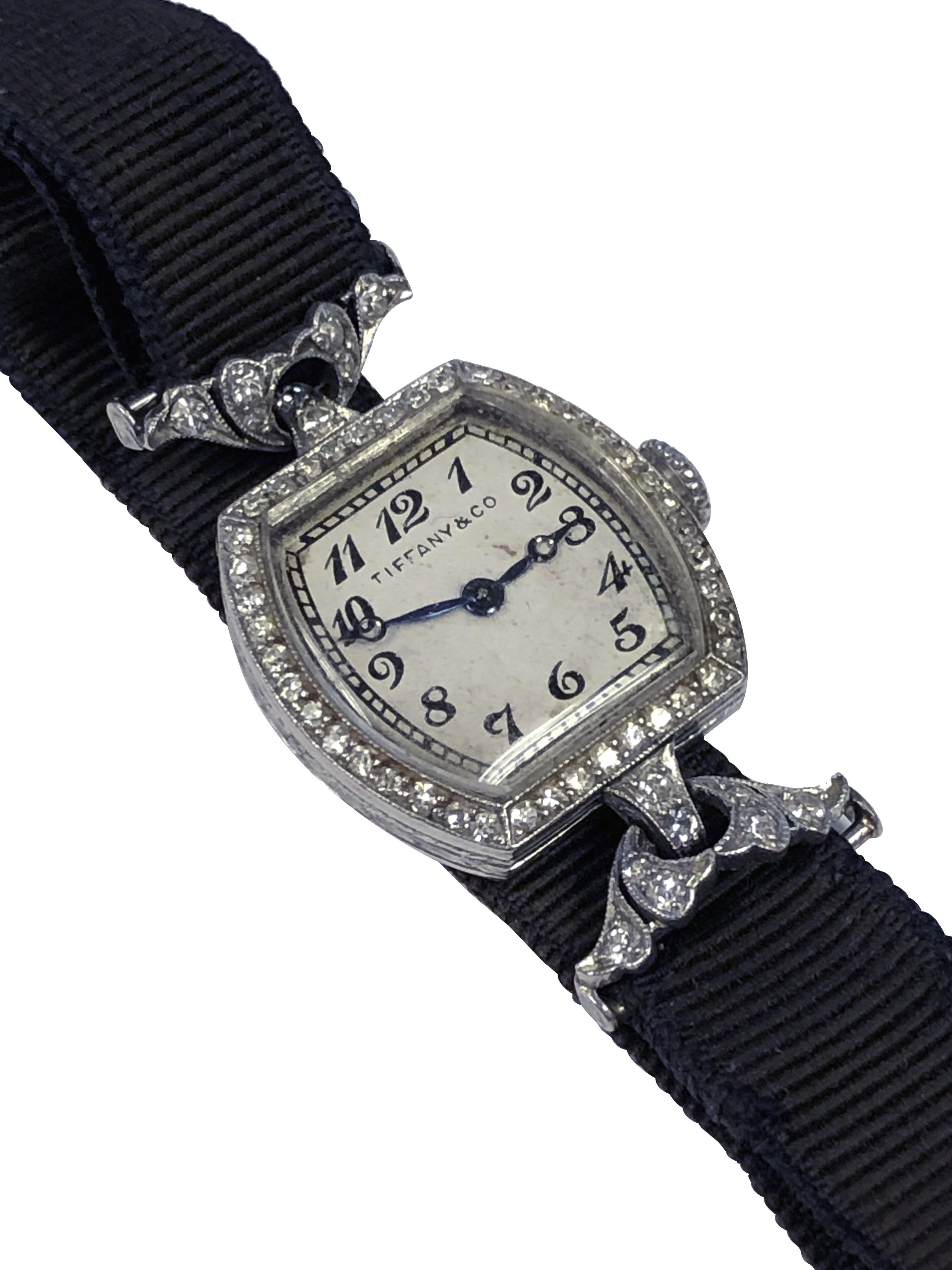 Vers 1920, Tiffany & Company a vendu au détail une montre-bracelet pour dames en platine et diamants, 18 x 18 M.M. Boîtier de forme coussin avec gravure à la main et diamants taille unique sertis dans la lunette. Les cornes flexibles serties de