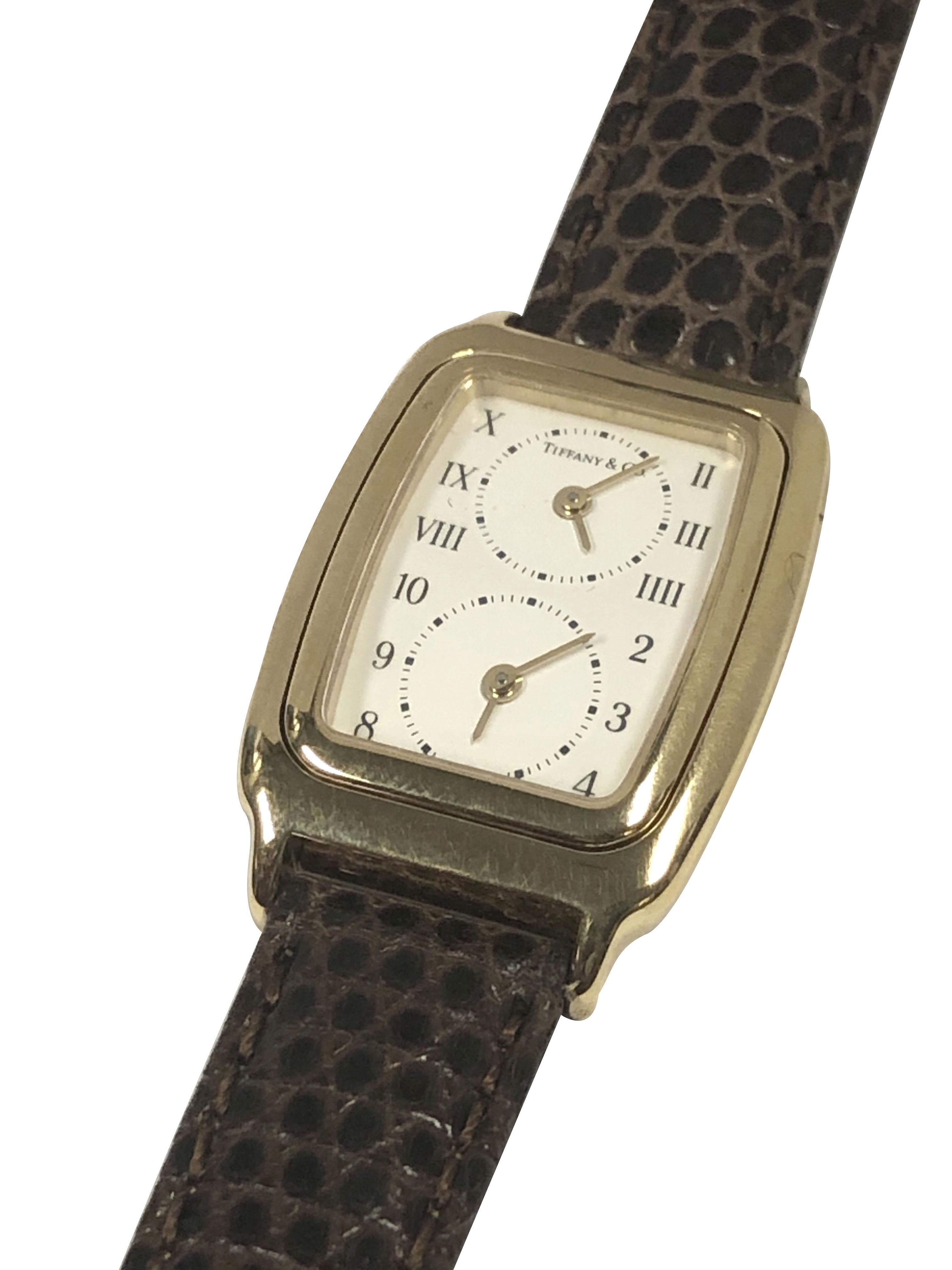 Circa 2000 Tiffany & Company 2 Time Zone Wrist Watch, 28 X 22 M.M. 18K Yellow Gold 3 piece case, 2 individual Quartz movements, White Dial. New Brown Lizard strap with original Tiffany & Co. Gold tone buckle. Comes in original Tiffany & Company