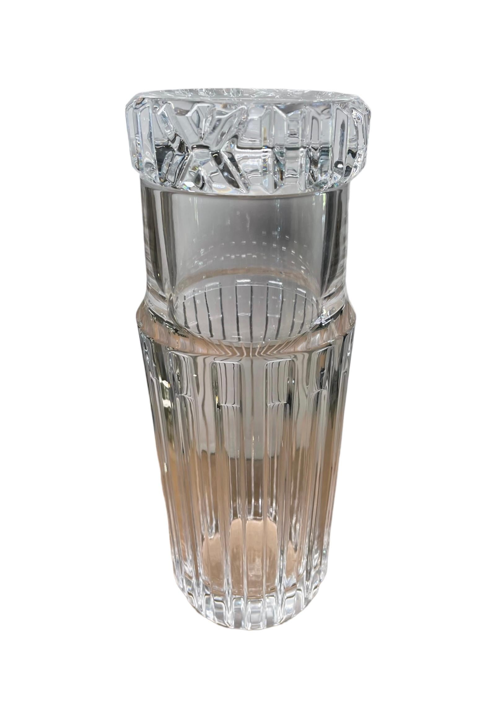 This is a Tiffany & Co “Atlas” Crystal bedside water carafe and glass. It depicts a cylindrical shaped reeded crystal tall and wide container with a glass that serves as a lid. This last one has a wide round base with cut crystal designs.