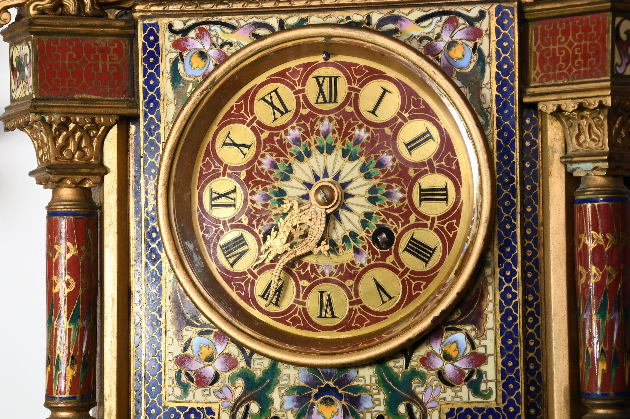 Tiffany's clock case with enamel roman numbers and bronze snake dials. At the top, the clock is adorned with an Indian palace gallery and dome that has a crane finial over it and dragon head legs. The rectangular clock base is supported by four