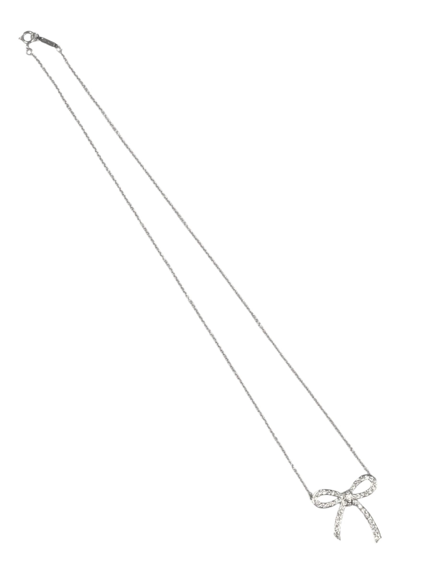 Circa 2020 Tiffany & Company Platinum Bow Pendant Necklace, measuring 3/4 x 3/4 inch and is set with Round Brilliant cut Diamonds totaling .27 Carats,  Suspended from a 15 inch Platinum chain. Signed Tiffany and comes in a Tiffany Suede Presentation
