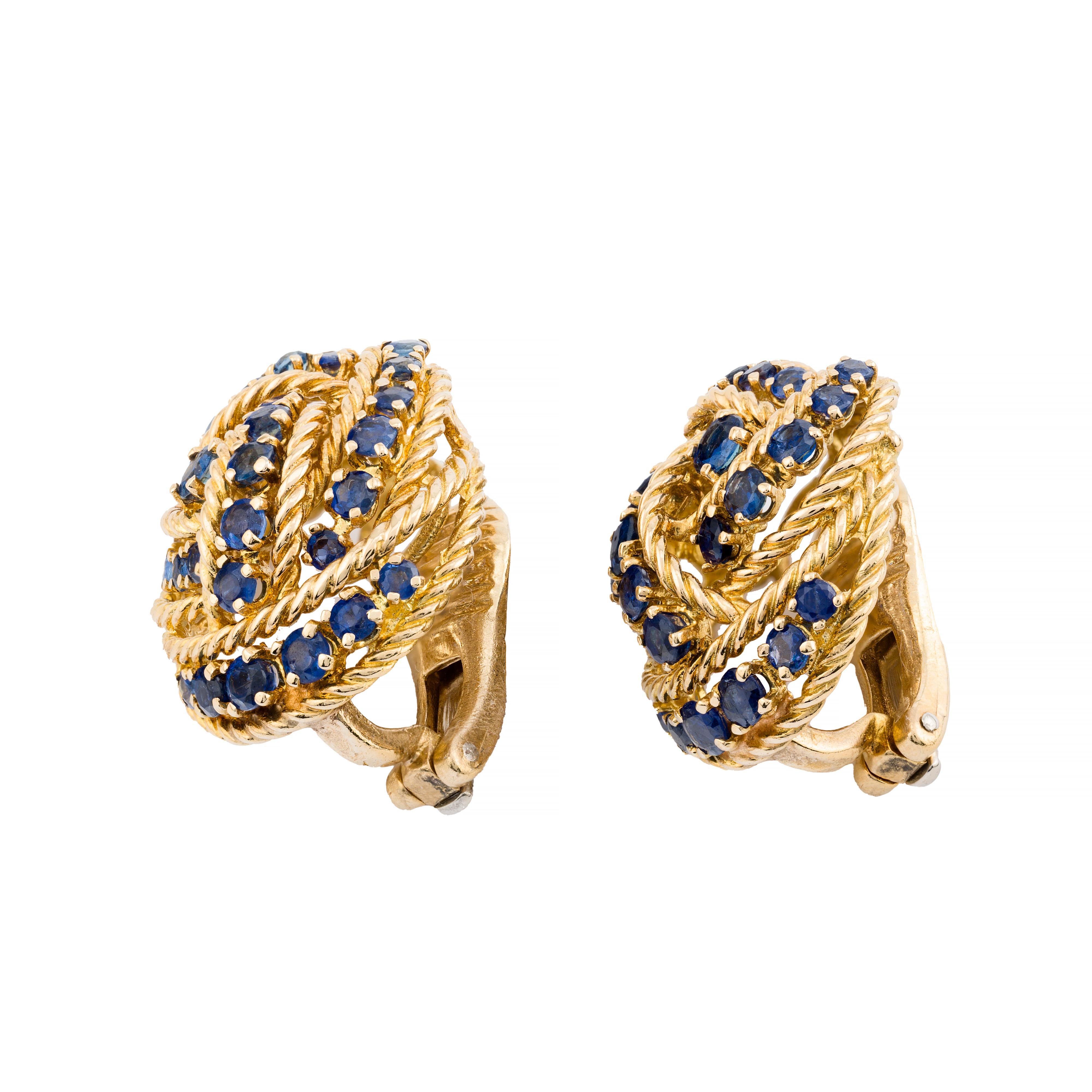 Aston Estate Jewelry présente

Boucles d'oreilles élégantes de Tiffany & Co. en or jaune 18 carats. Chaque boucle d'oreille présente un design captivant avec des saphirs bleus ronds, sertis de manière complexe dans des anneaux de corde en or