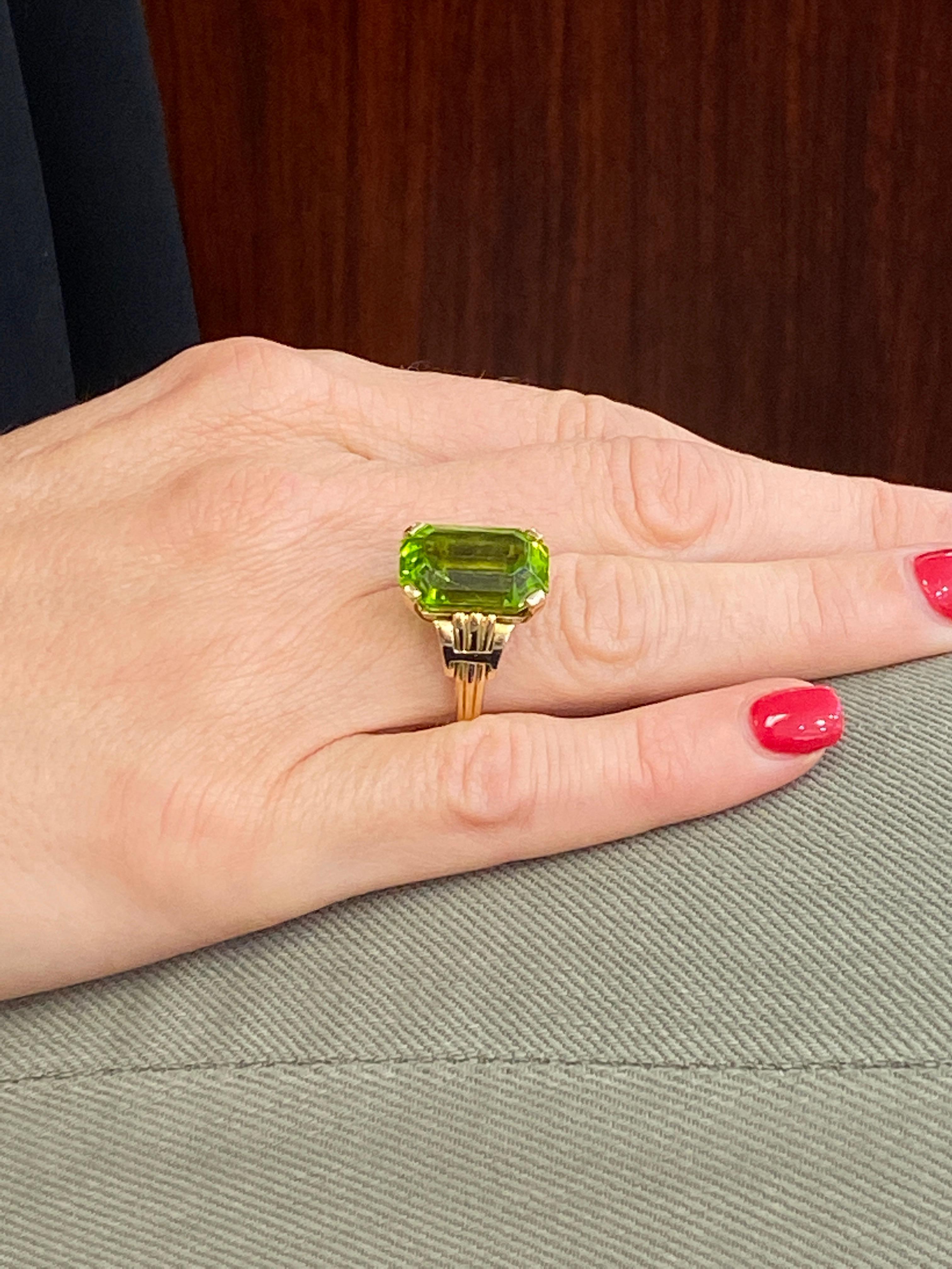 Tiffany & Company Vintage Peridot Ring fashioned in 14 karat yellow gold. The emerald cut peridot gemstone weighs approximately 12 carats, has a beautiful yellowish green color, and has been certified by the AGL. The peridot has not had any