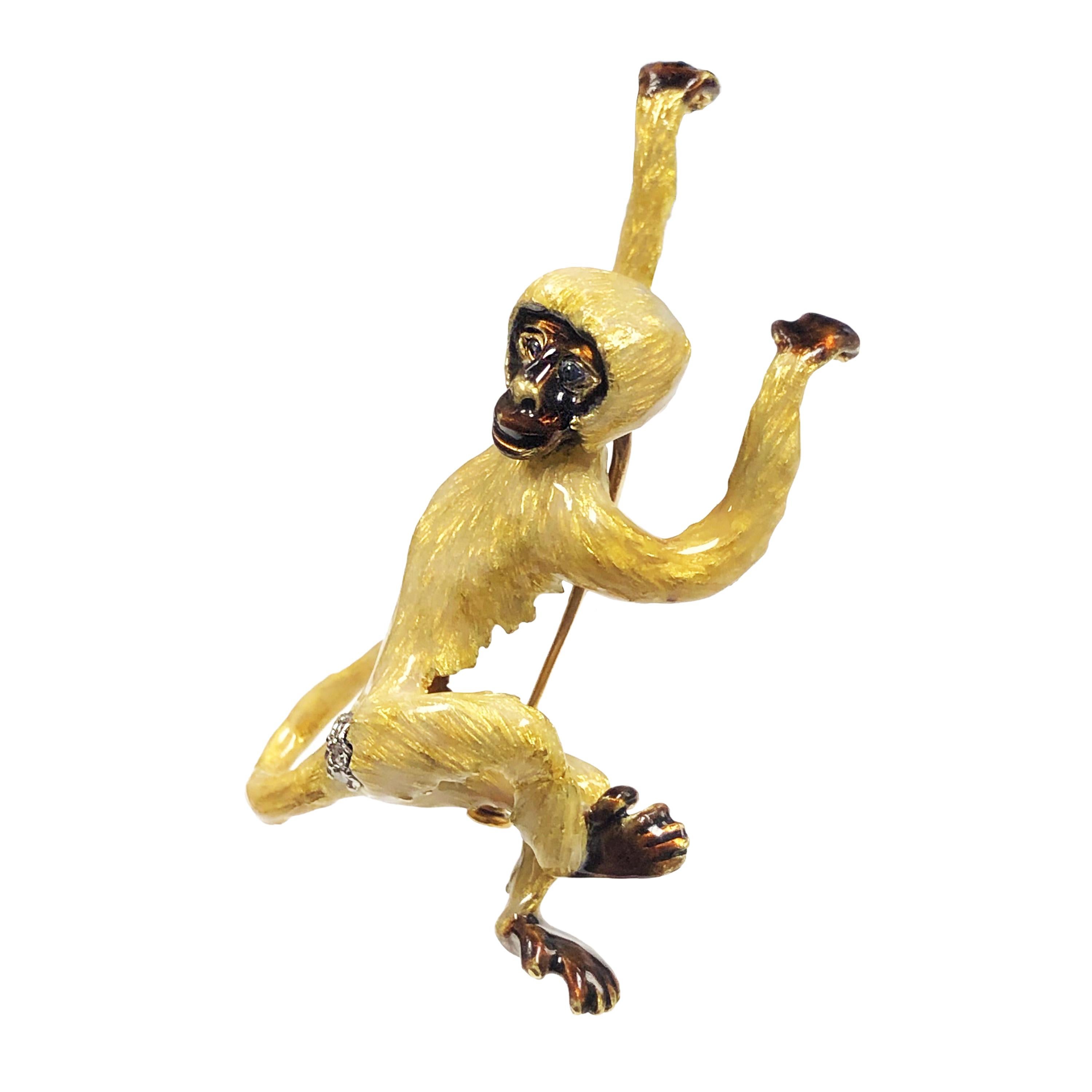 Circa 1970s Very Whimsical 18K Yellow Gold Monkey Brooch, measuring 2 1/4 inches in length X 1 3/8 inch wide. This detailed piece is completely finished in a light Tan - Yellow Guilloche Enamel with Brown Hands and Feet and a Brown Face. Sapphire