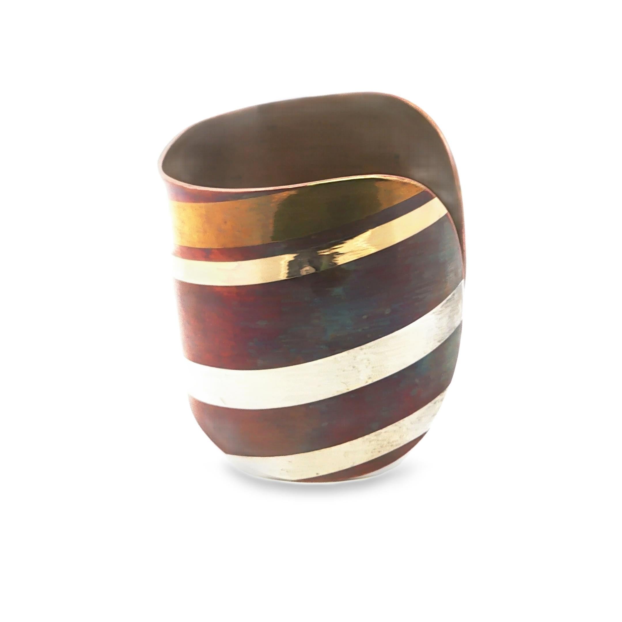 This striking cuff bracelet is a testament to modern design by Tiffany & Co. Crafted in 1980, it features a harmonious blend of copper, gold, and silver, creating a captivating interplay of colors and textures. The bracelet's surface showcases a