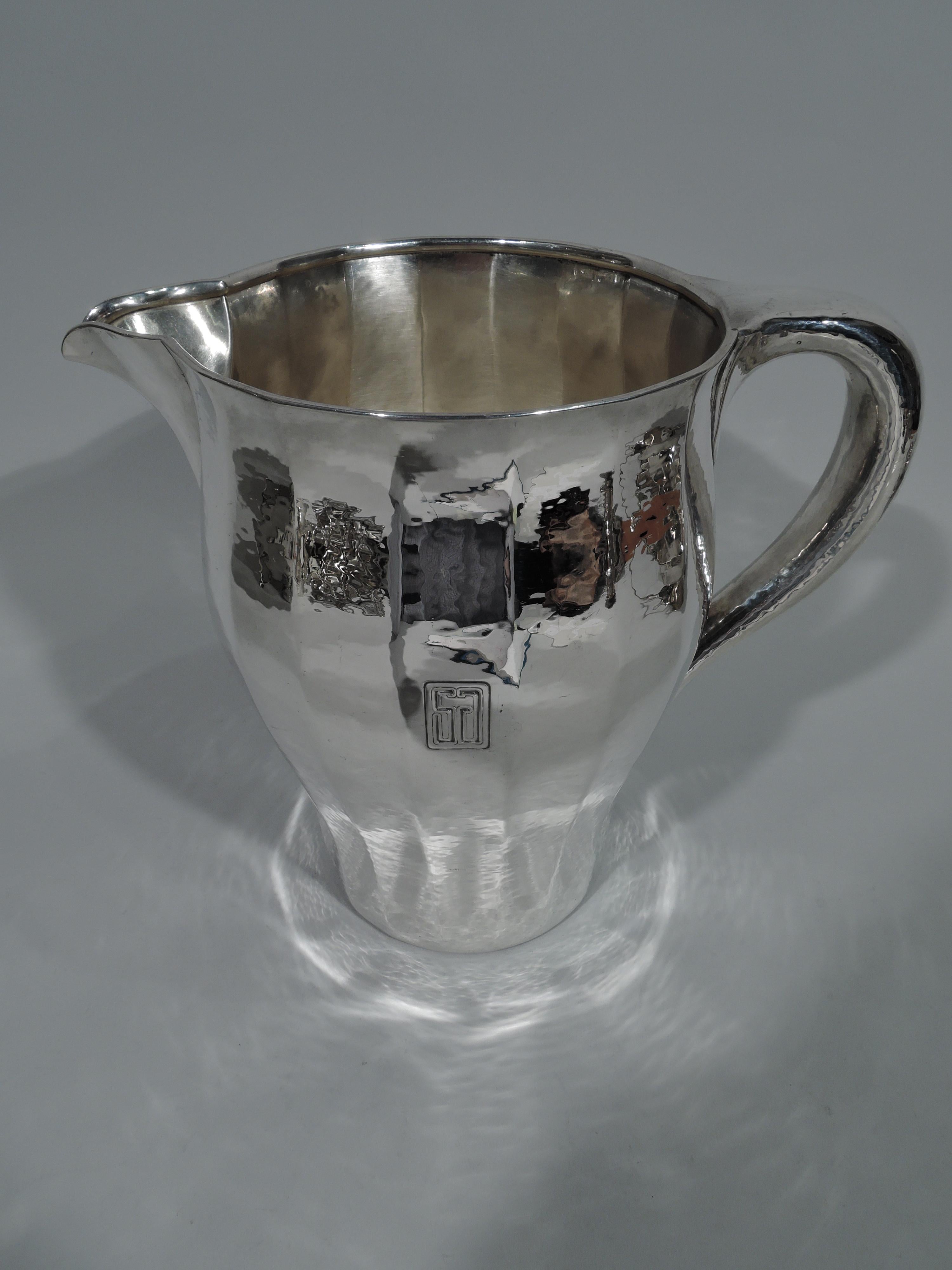 Craftsman hand-hammered sterling silver water pitcher. Made by Tiffany & Co. in New York, circa 1909. Softly faceted baluster with V-spout and C-scroll handle. Nice rippling shimmer. Rectangular frame with two-letter monogram. Fully marked including