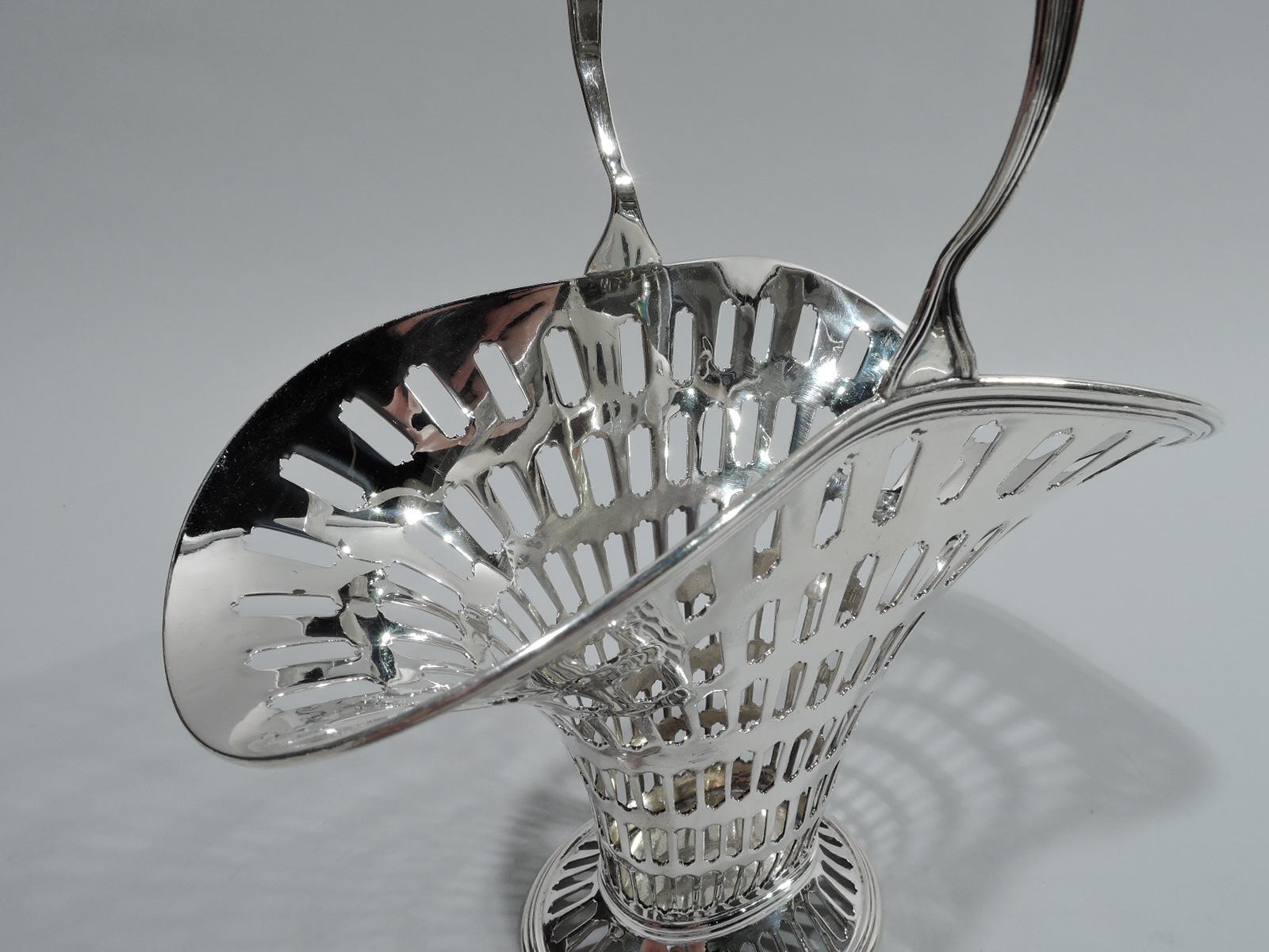 Edwardian Modern sterling silver basket. Made by Tiffany & Co. in New York. Tapering and “squashed” ovoid body with flared mouth and spread foot. Reeded and tapering stationary handle. Graduated tubular piercing. Fully marked including maker’s
