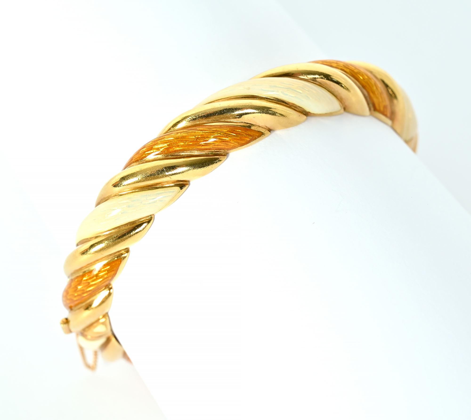 Tiffany-Emaille-Armreif mit ungewöhnlichen Farben. Es  hat drei gedrehte Bänder - eines in Gold und die beiden anderen mit perlmuttem Elfenbein und bernsteinfarbenen Emaille. Das Scharnierarmband hat einen Verschluss und eine Sicherheitskette.  Er