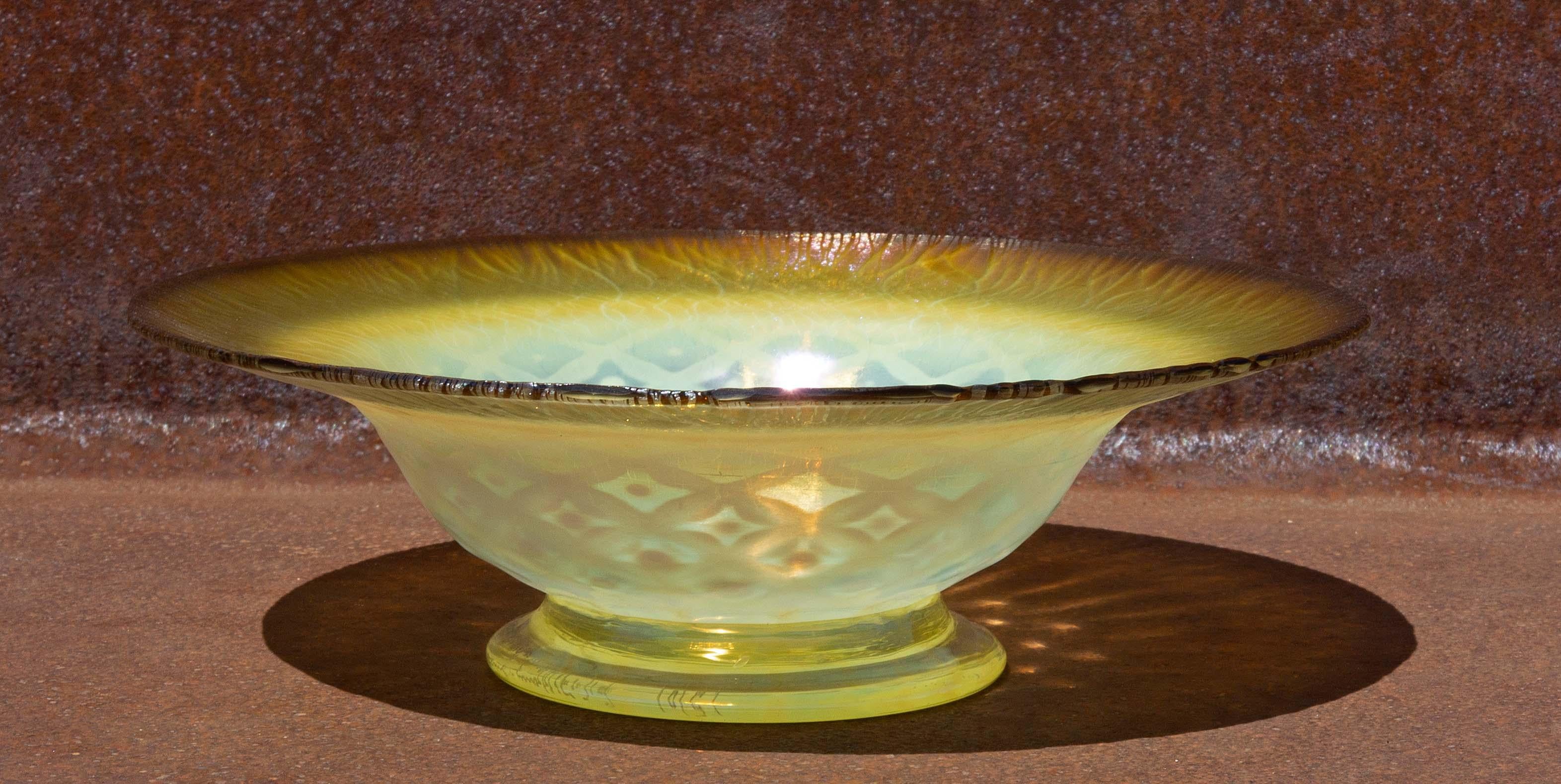 Louis Comfort Tiffany signed Favrile art glass bowl. Round with wide rim on a circular foot. Iridescent gold, pink and mauve colors. Lace pattern interior. 8 3/4