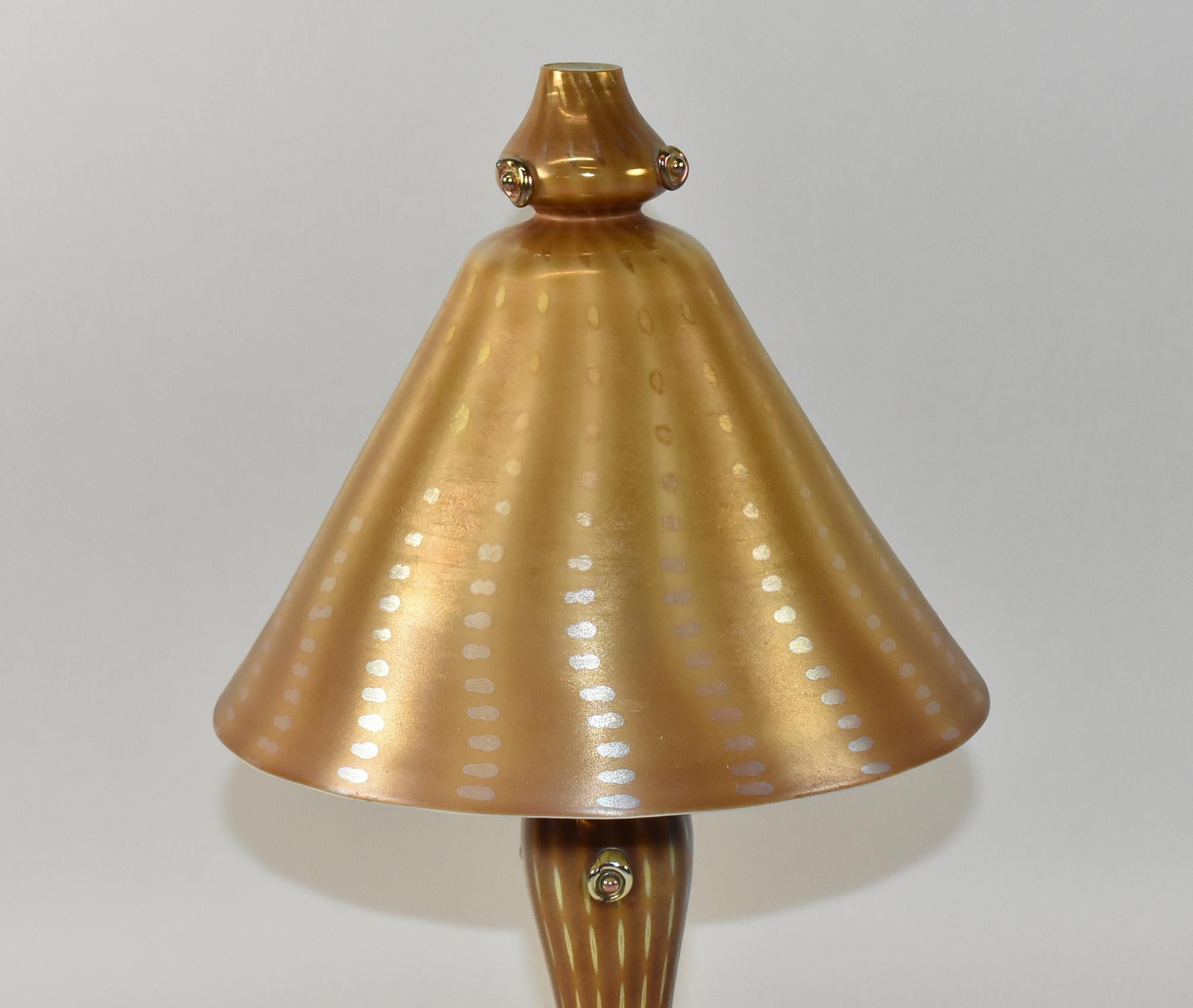 Preciosa lámpara de tocador de cristal Tiffany Favrile de principios del siglo XX. La lámpara tiene una pantalla cónica de cristal y una base de balaustre con decoloración dorada/ámbar de motivos 
