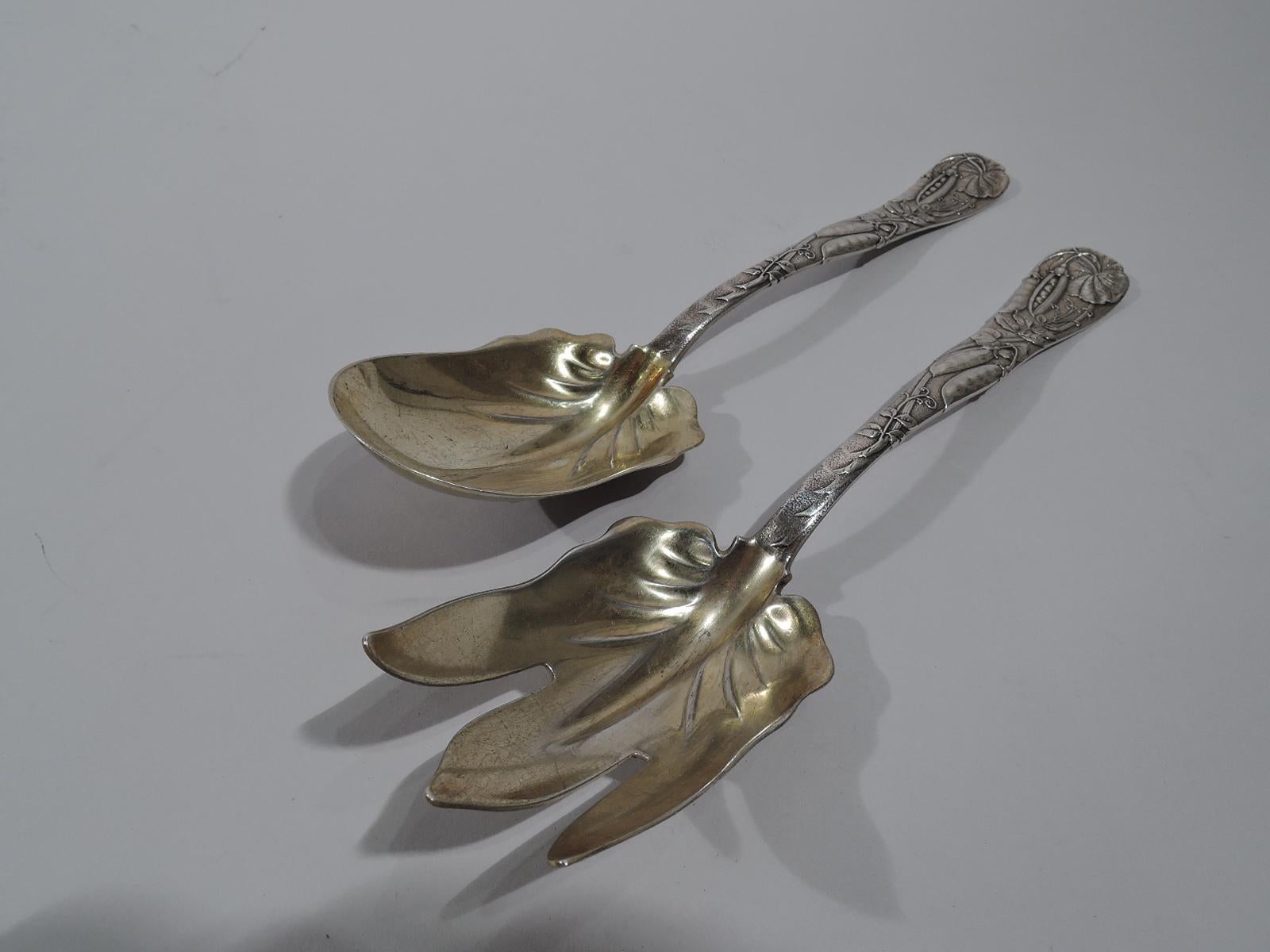 Very desirable sterling silver salad serving pair in Vine. Made by Tiffany & Co. in New York. This pair comprises spoon and fork. Each: Loosely arranged wraparound pea pod vine on tapering and gently waving handle. Bowl and shank gilt-washed with