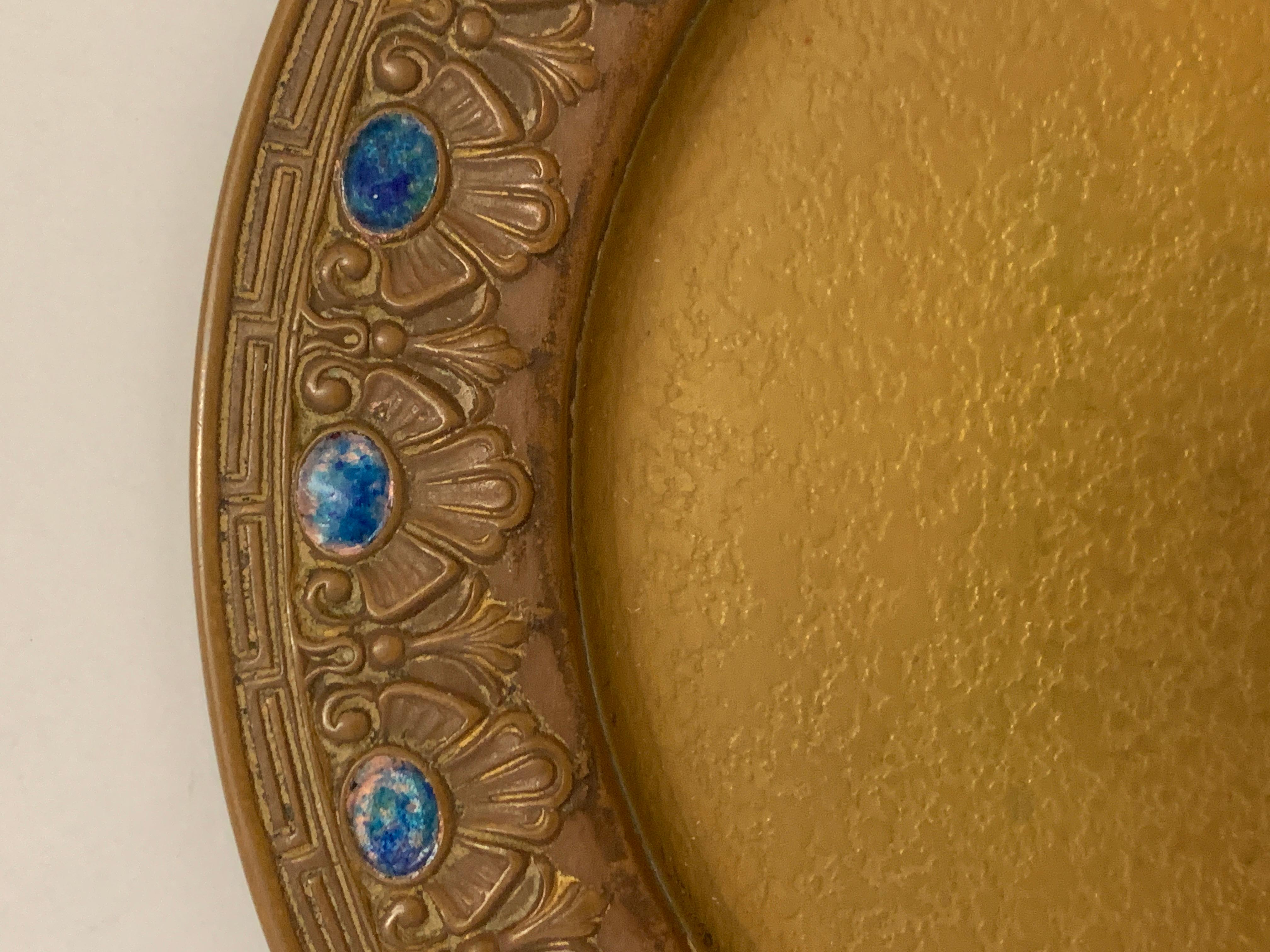 A Louis C. Tiffany Furnaces, inc. Favrile bronze plate with enamel inset ovals and rim decoration. It is marked on the bottom along with the number 309. It measures approx 8.25 inches in diameter and is approx .625 of an inch deep. It has five cast