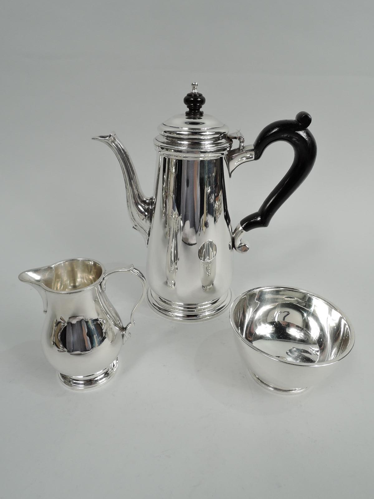 Georgian-style sterling silver 3-piece coffee set on tray. Made by Tiffany & Co. in New York. Coffeepot: Upward tapering body with curved bottom and round stepped foot. Fluted s-scroll spout and hinged and domed cover with stained-wood and sterling