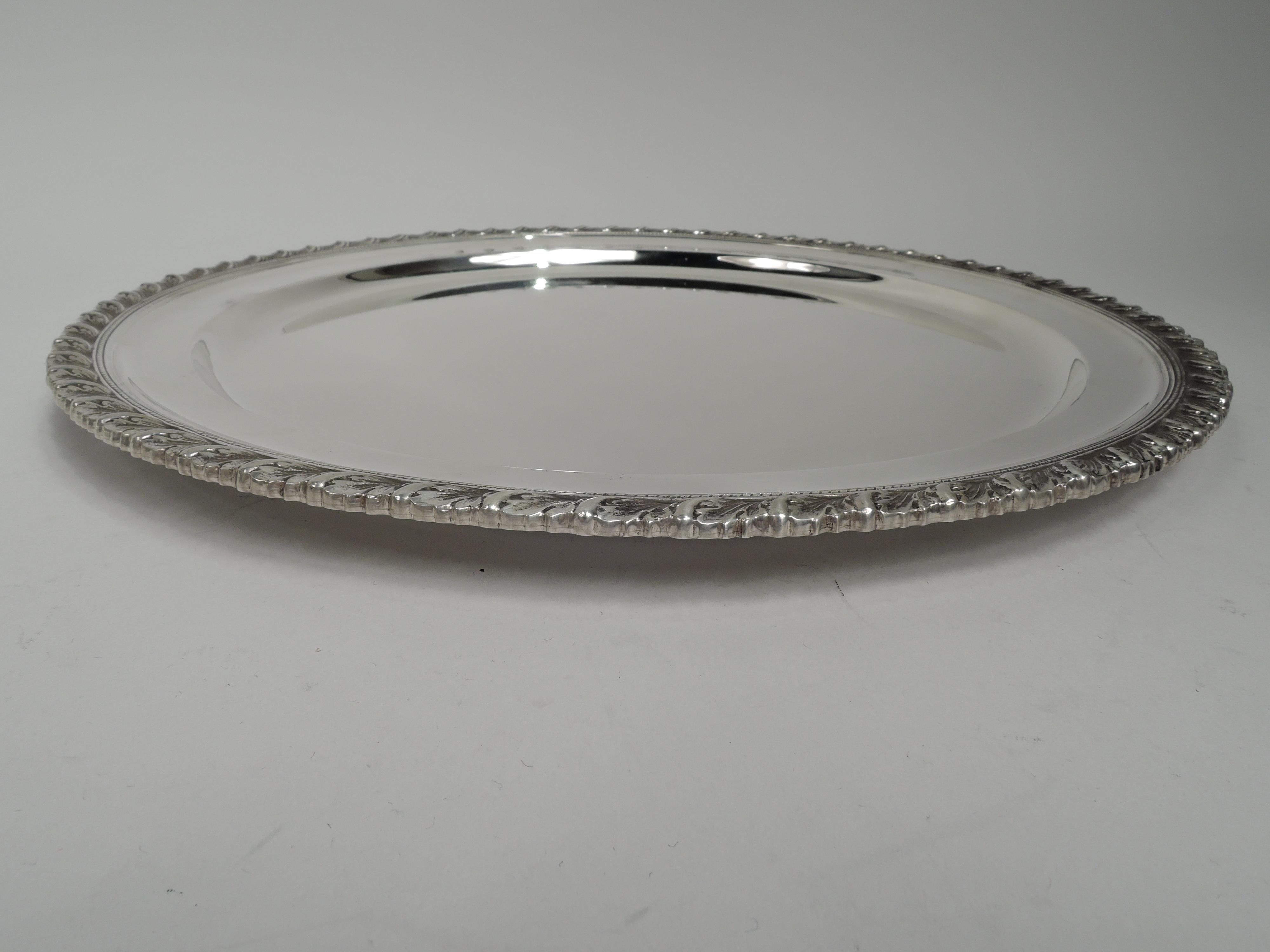 Georgian-style sterling silver tray. Made by Tiffany & Co. in New York. Round well and and cast gadrooned rim. Traditional with nice heft. Fully marked including maker’s stamp, pattern no. 18868, and director’s letter M (1947-56). Heavy weight: 30