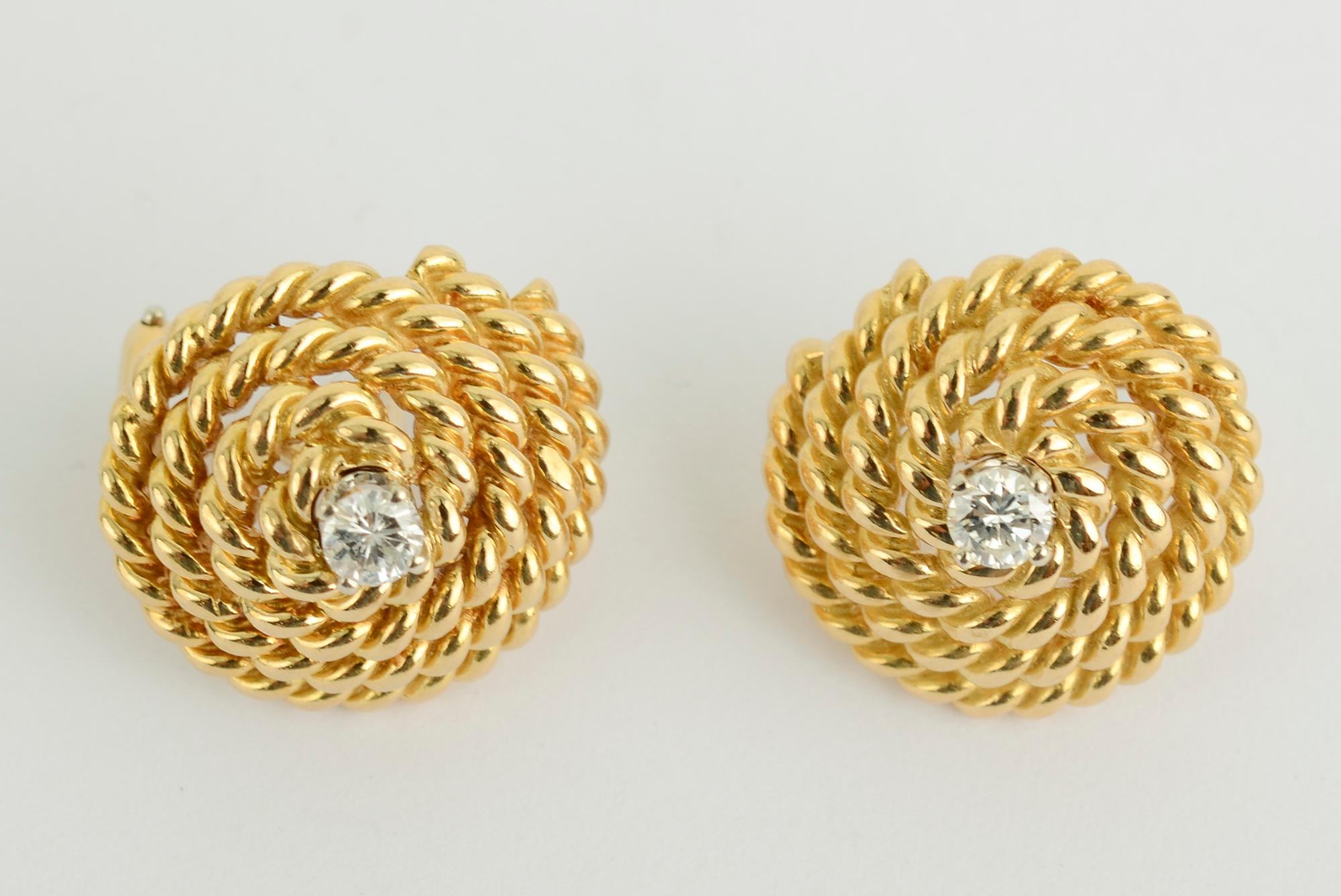 Die klassischen Tiffany-Ohrringe mit Spirale haben den ungewöhnlichen Zusatz eines zentralen Diamanten. Jeder Stein hat etwa 1/4 Karat. Die Rückseiten sind Pfosten und Klammern. Die Ohrringe sind 3/4 Zoll im Durchmesser. Verkauft mit blauem