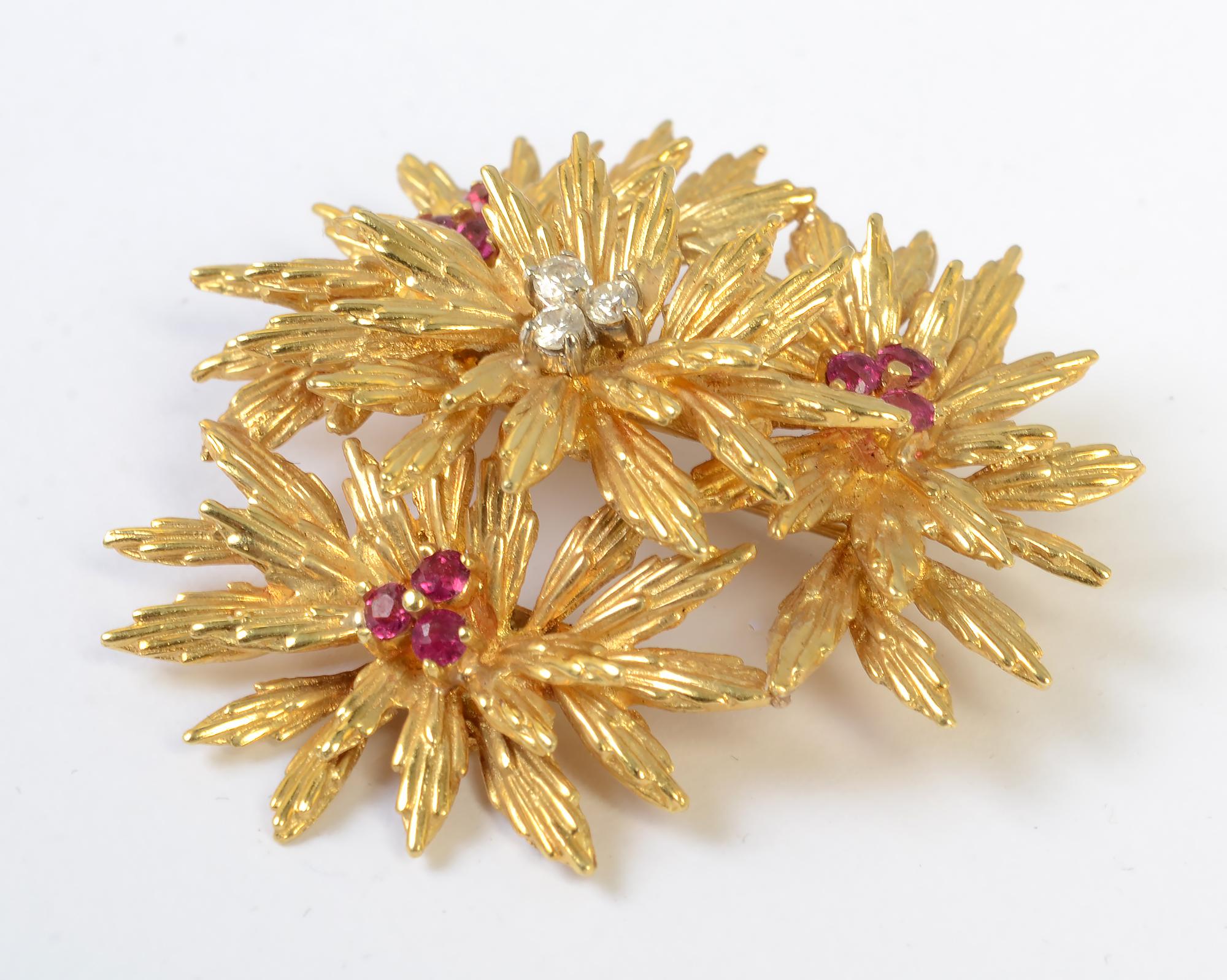 Wonderfully textured and three dimensional brooch by Tiffany with four spiked flowers. Three flowers on the bottom layer are centered with rubies. Overlapping them is a flower with three diamonds in the center.
The brooch is 1 3/4 inches in diameter