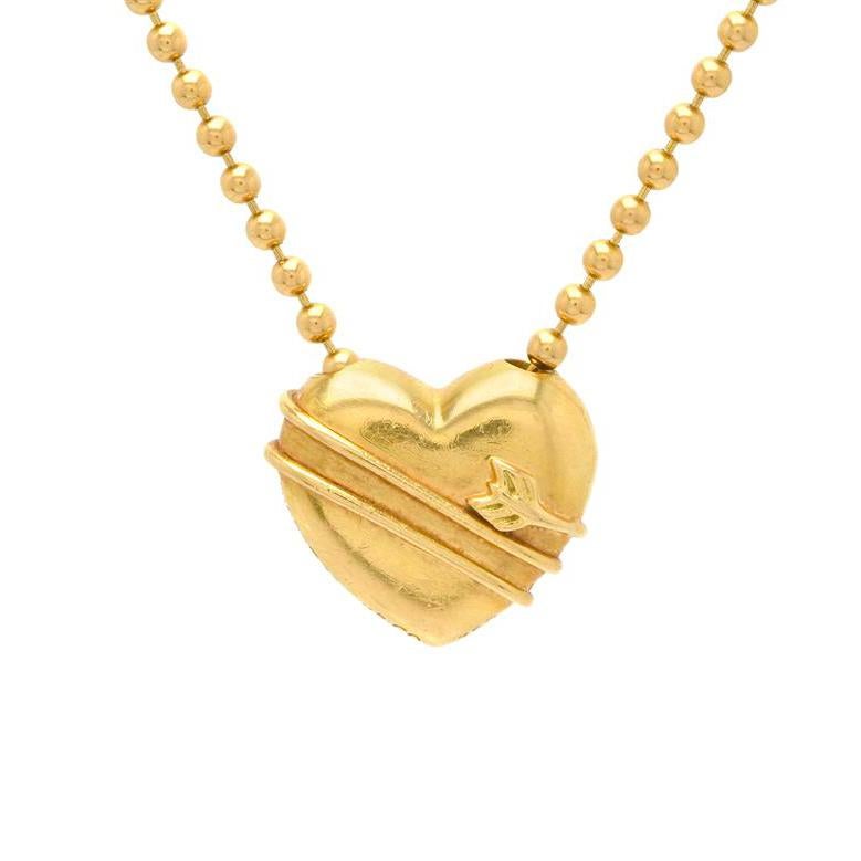 A golden heart pendant with chain by Tiffany & Co in 18k yellow gold. The pendant is in the shape of heart hugged by an arrow as a symbol of love. It is signed and numbered.