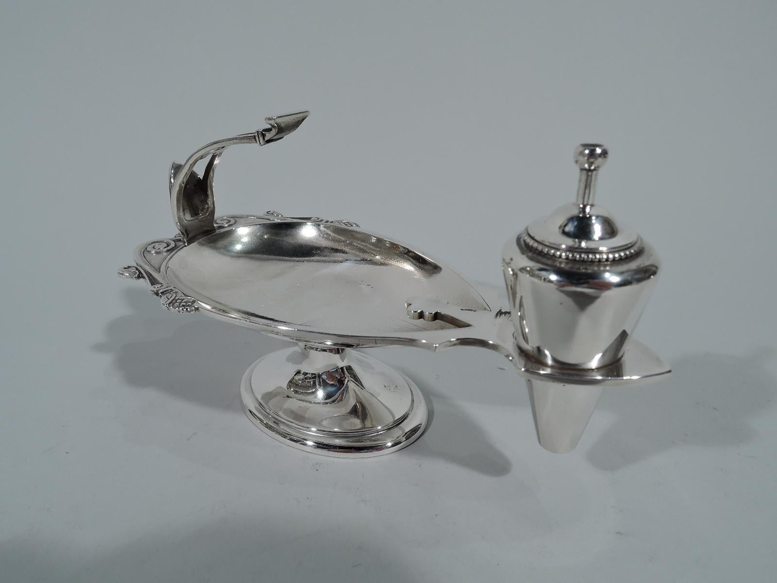 Greek Revival sterling silver cigar lighter in form of ancient oil lamp. Made by Tiffany & Co. in New York. Oval bowl with rim scrolls and buds. Flying open scroll handle with palmette thumb rest. Raised oval foot and conical receptacle for holding
