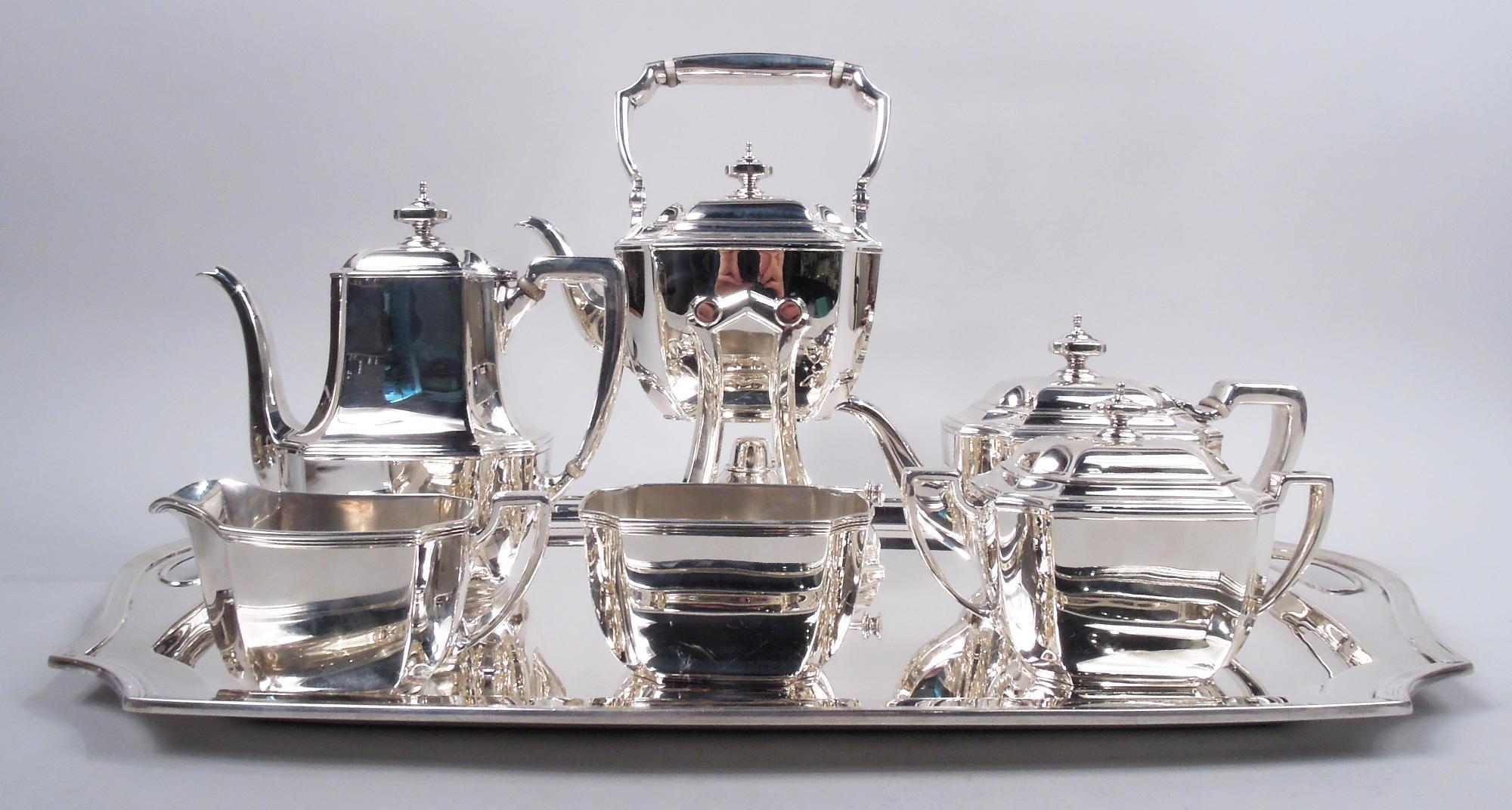 Hampton sterling silver coffee and tea set on tray. Made by Tiffany & Co. in New York, ca 1930. This set comprises 7 pieces: Hot water kettle on stand, coffeepot, teapot, creamer, sugar, and waste bowl on tray. Rectilinear with gently curved sides