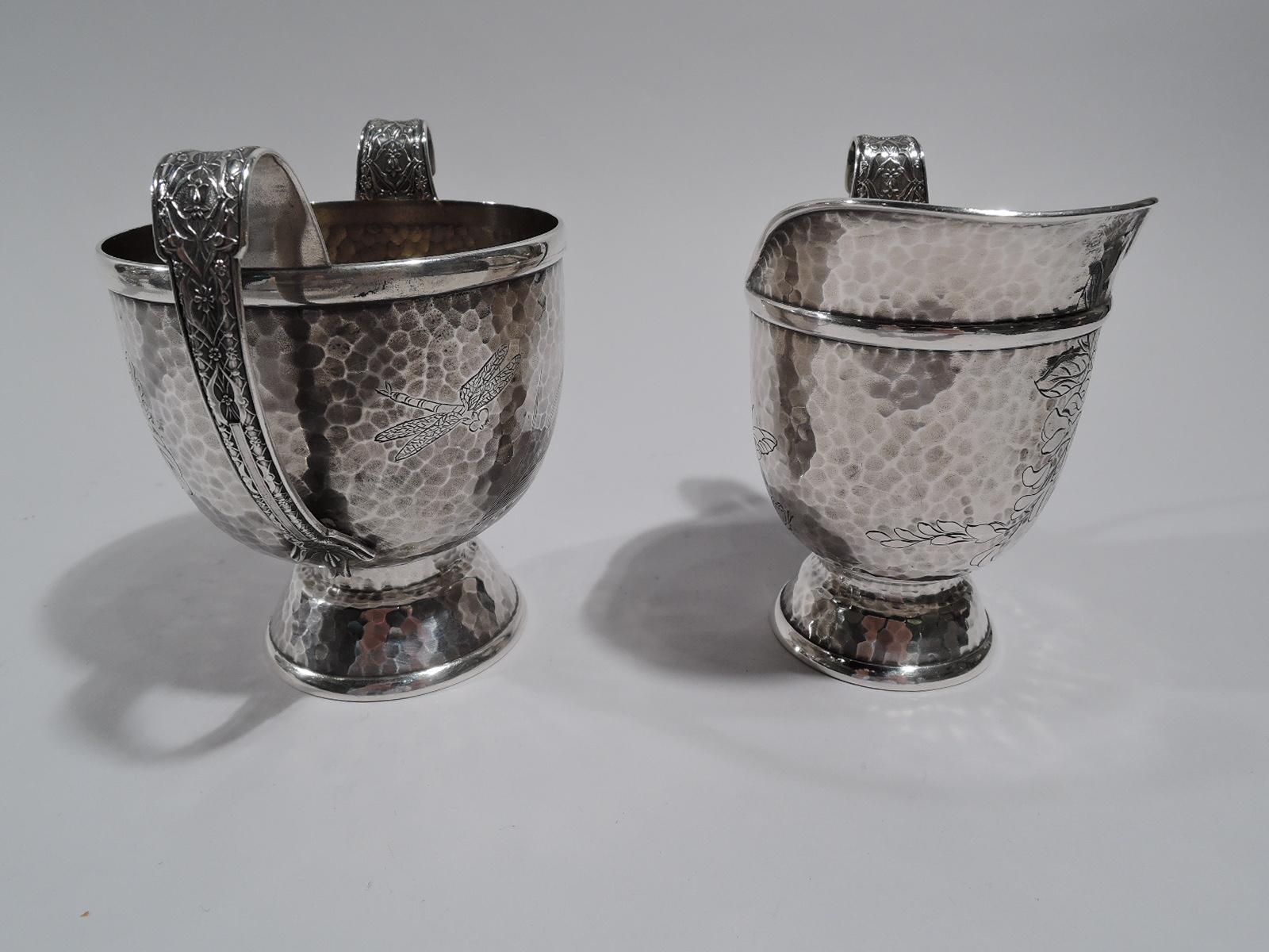 Japonesque sterling silver creamer and sugar. Made by Tiffany & Co. in New York.

Each: Urn body on domed foot handles high looping. Interior gilt washed. Creamer has helmet mouth. Engraved insects (dragonfly and butterfly), flowers, and