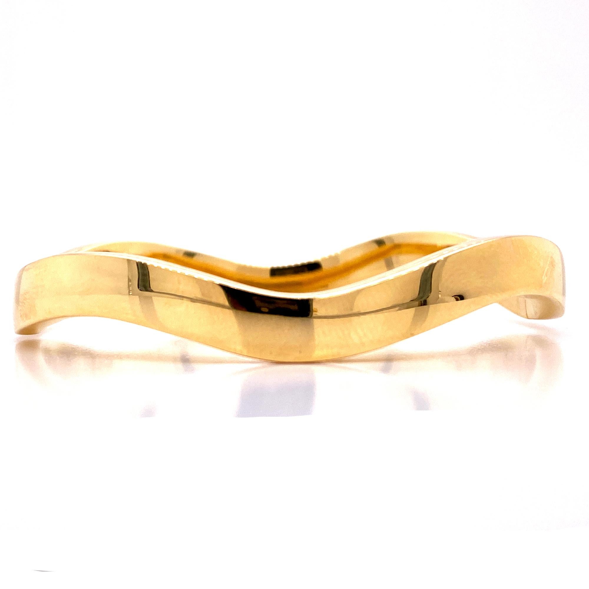 Beautiful 18 karat yellow gold wave bangle by Tiffany & Co. Italy. The bangle measures 6.8mm in width, 2.3 inches  in diameter, and 7 inches in circumference. Signed Italy Tiffany & Co. 750