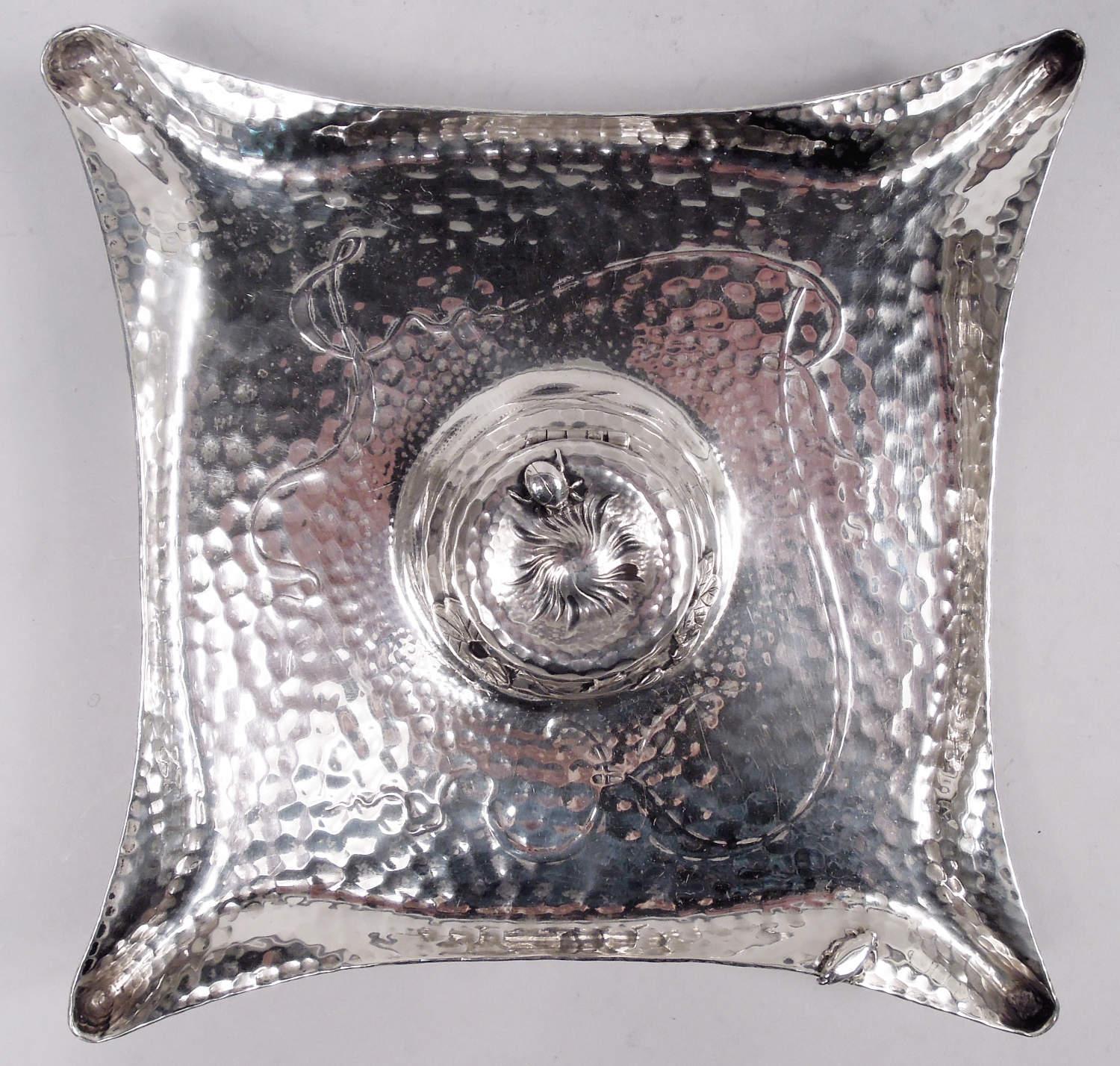 Tintero japonés de plata de ley. Fabricado por Tiffany & Co. en Nueva York, hacia 1881. Cuadrado con lados cóncavos y esquinas estriadas sobre soportes de volutas y junquillos de fundición. Cuenco de balaustre montado en el centro con tapa abatible.